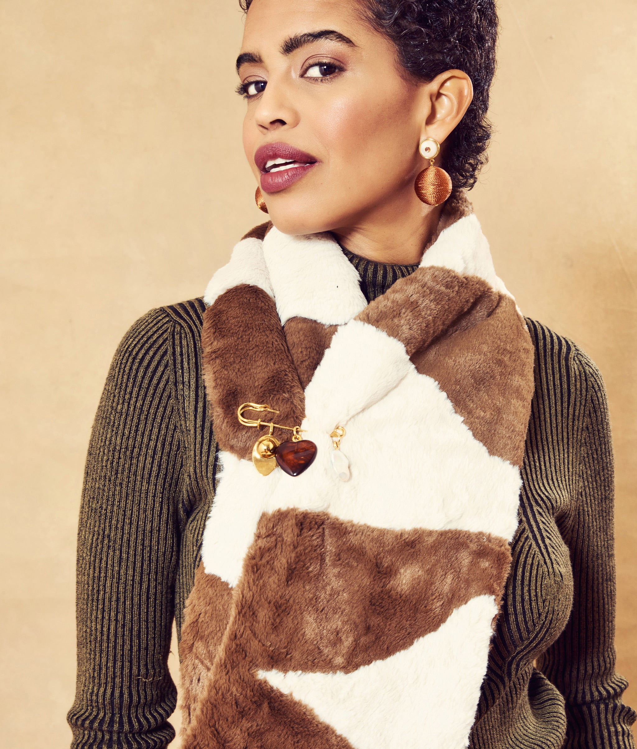 Model on tan backdrop wears brown ribbed turtleneck, slacks, and Fur Stole in Mesa around her neck, with Memento Pin.