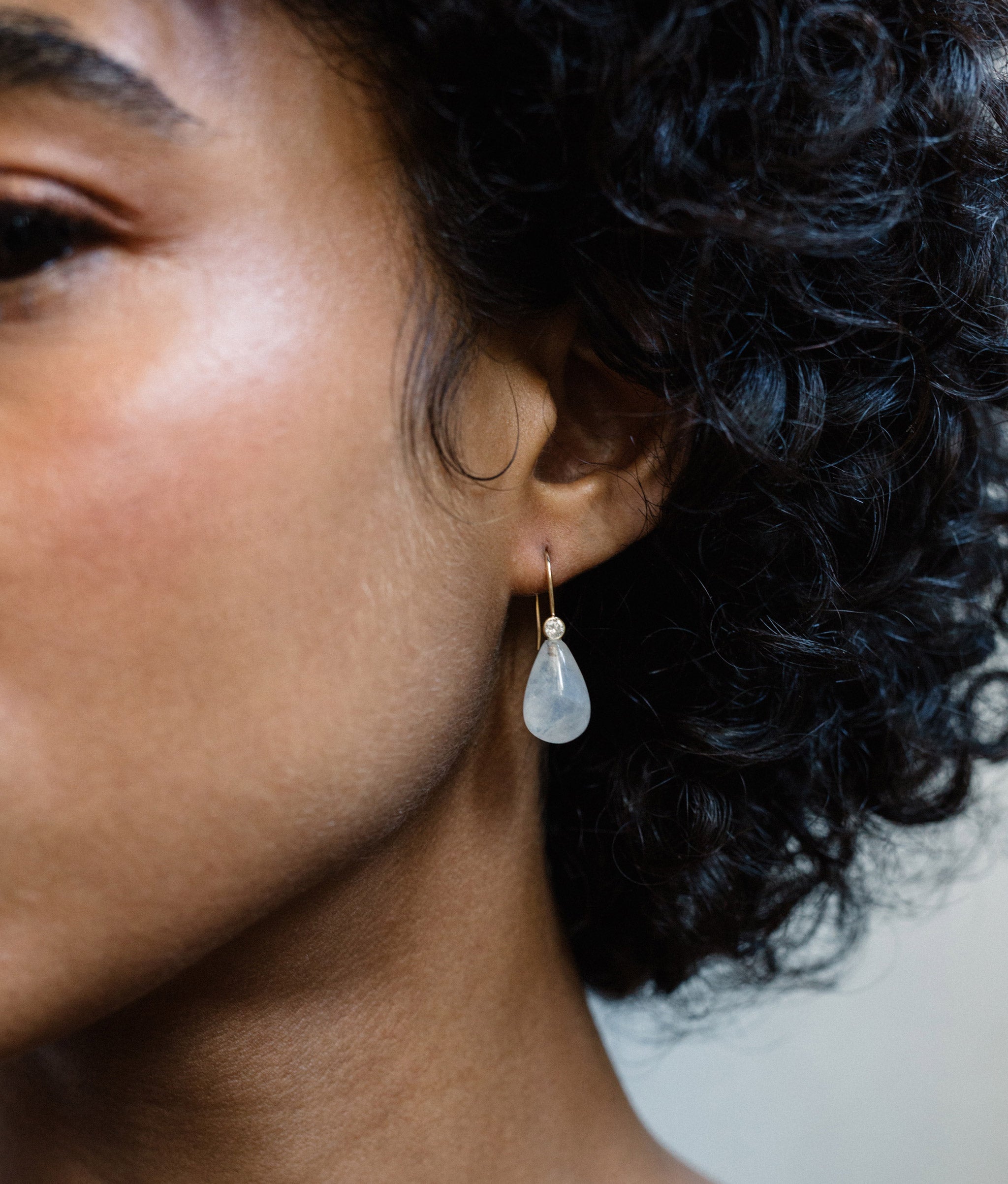 Model on grey backdrop wears Moonstone & Diamond 14K Earrings.