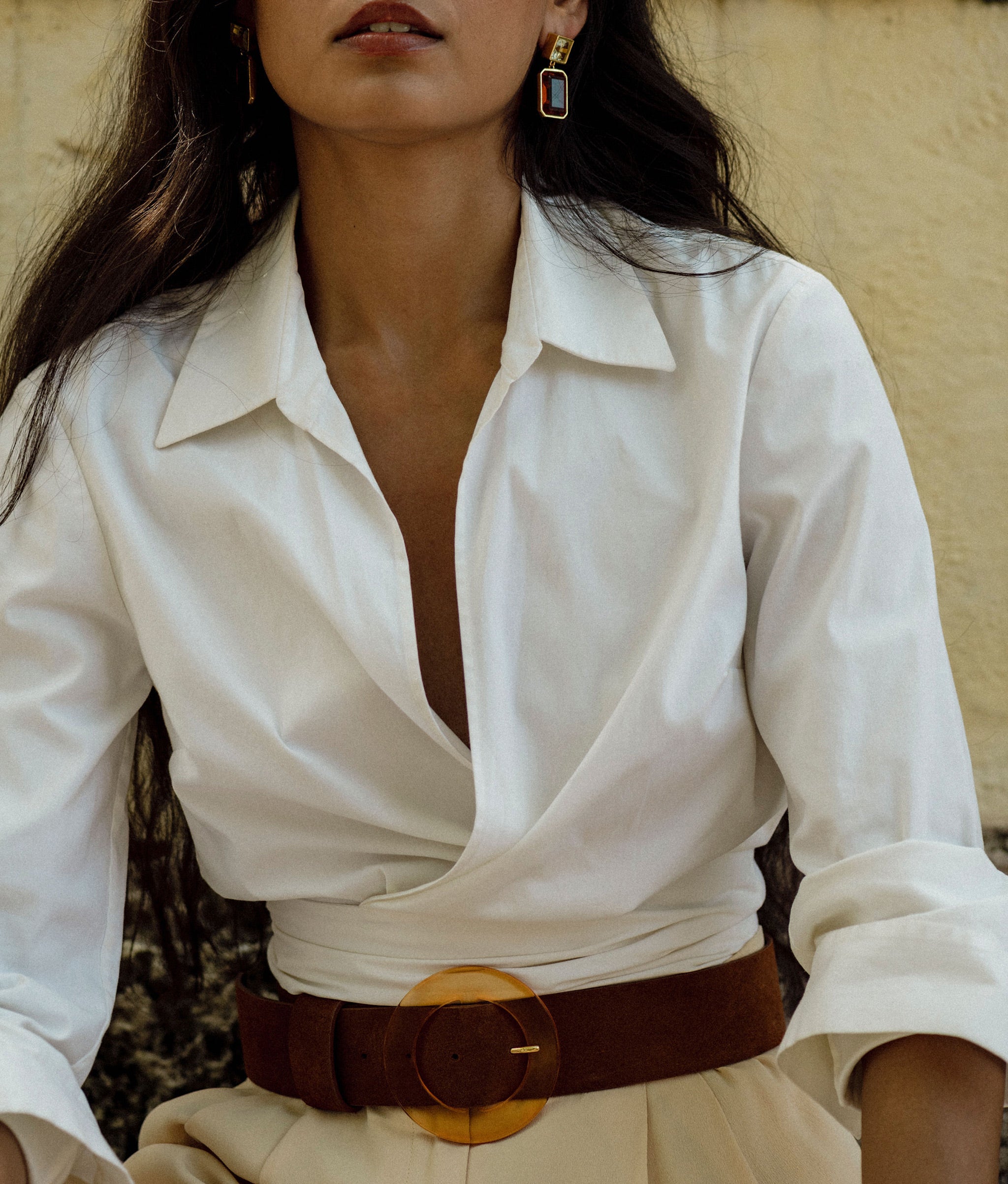 Model on cream wall wears white shirt with Louise Belt in Sienna.