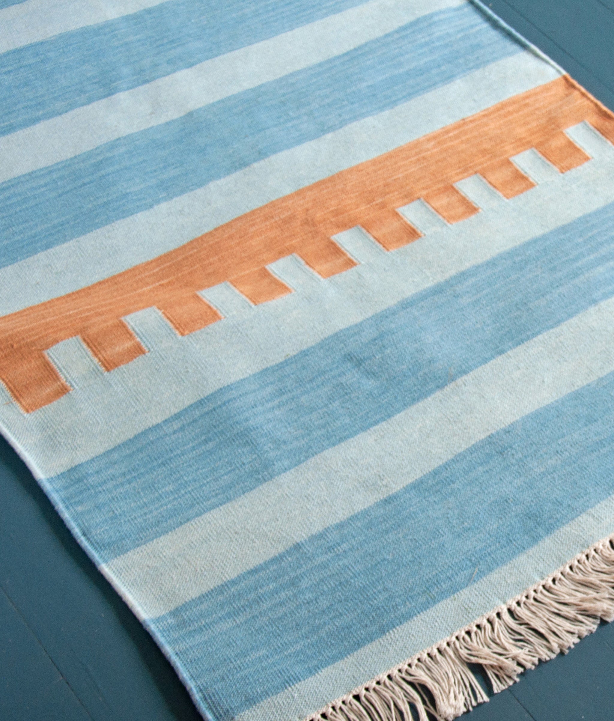 Andes Stripe in Sky Runner shown on blue-painted wood floor.