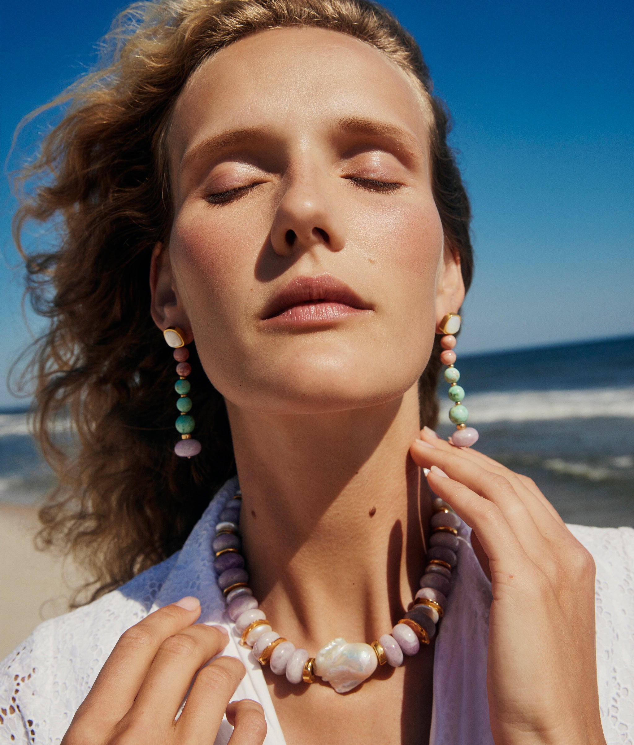 Model with sun on her face wears Costa Nova Earings and Provence II Necklace.