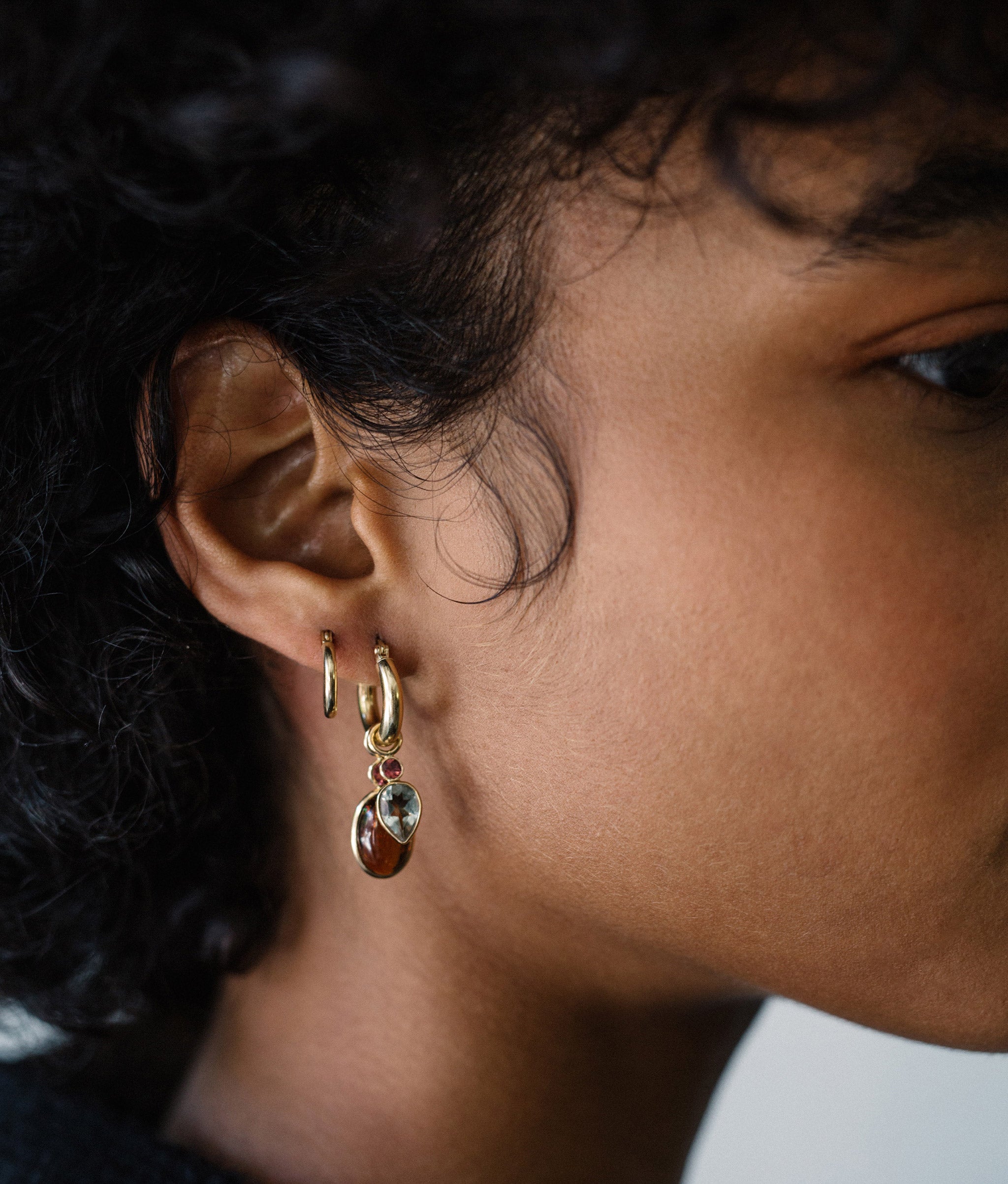 Model in close-up profile wearing the 12mm 14k gold hoop earrings with charms.