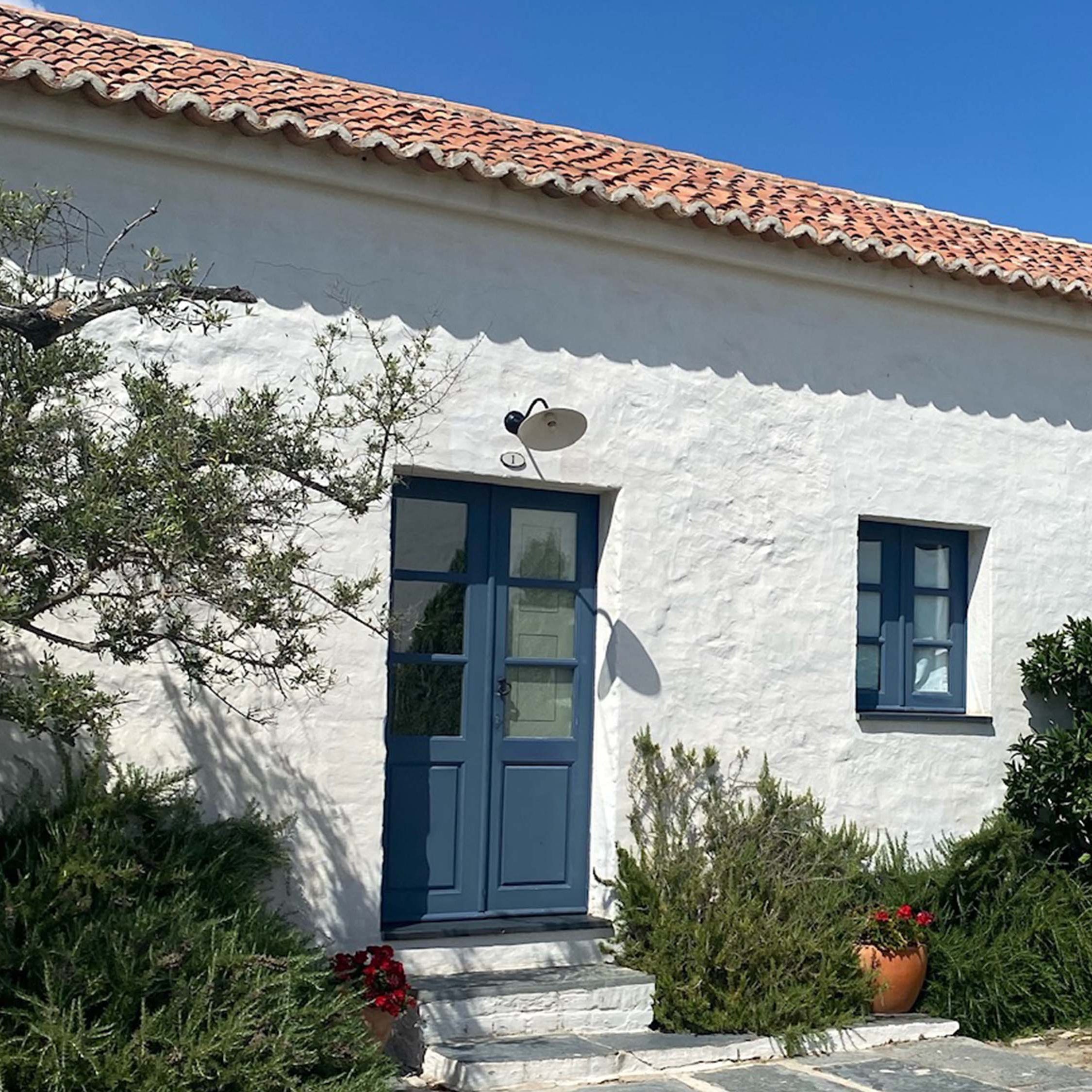 White stucco bungalow with tiled roof and blue door