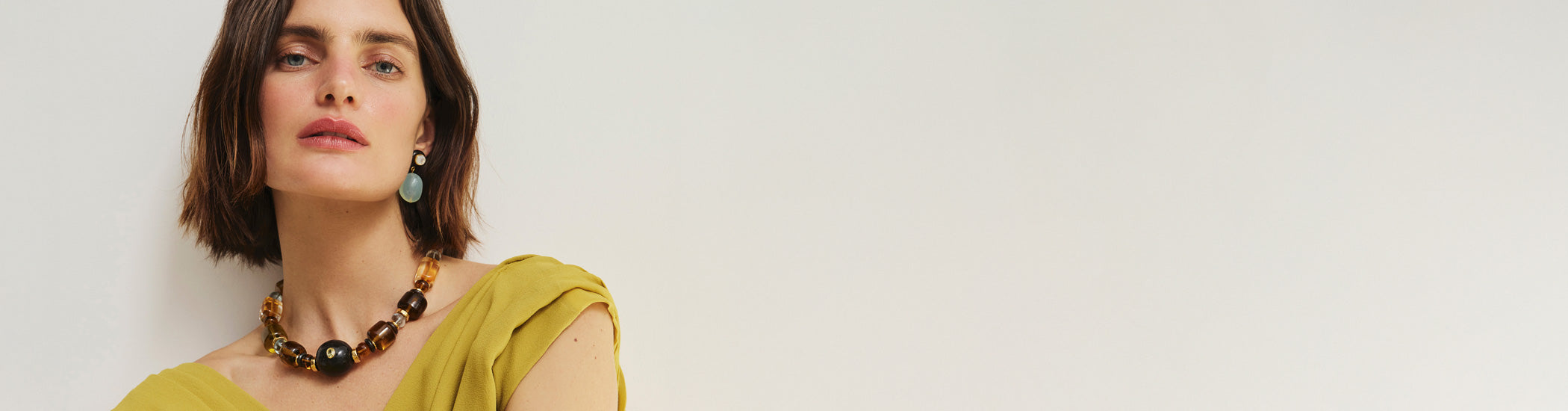 Model on grey backdrop wears chartreuse top with Desert Mirage Collar and Laurel Earrings