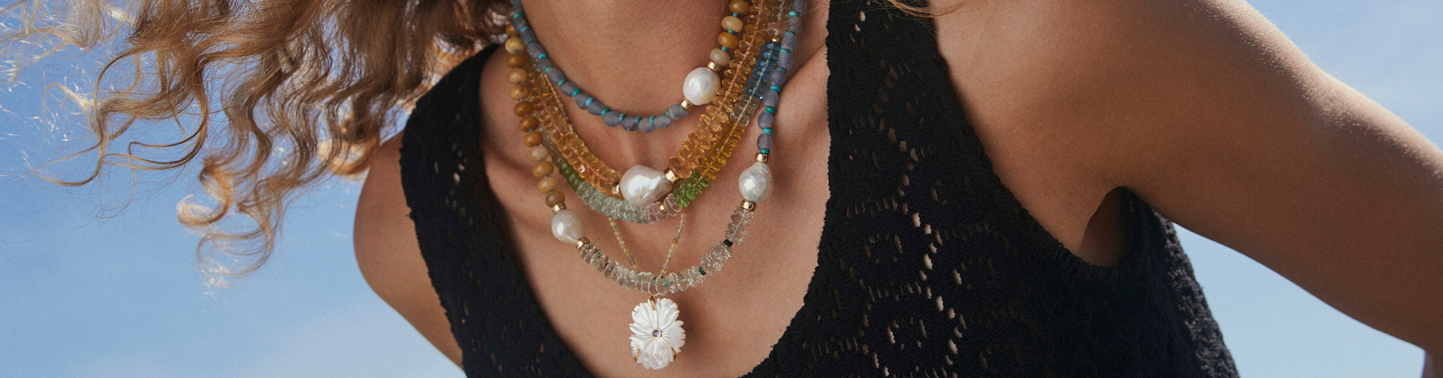 Model in black tank wears assorted colourful necklaces