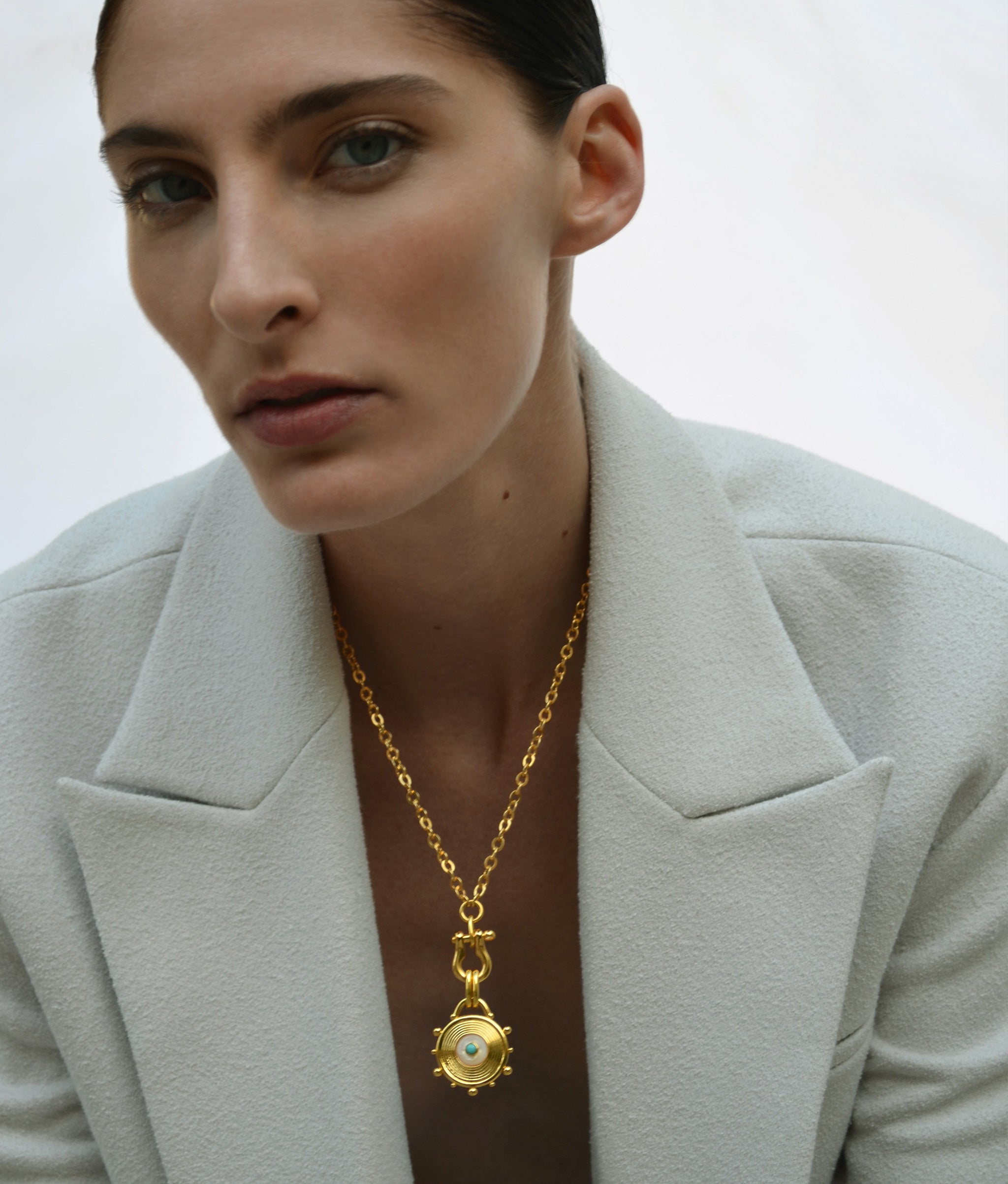 Model on white backdrop wears cream wool blazer with Helm Necklace in Pearl.