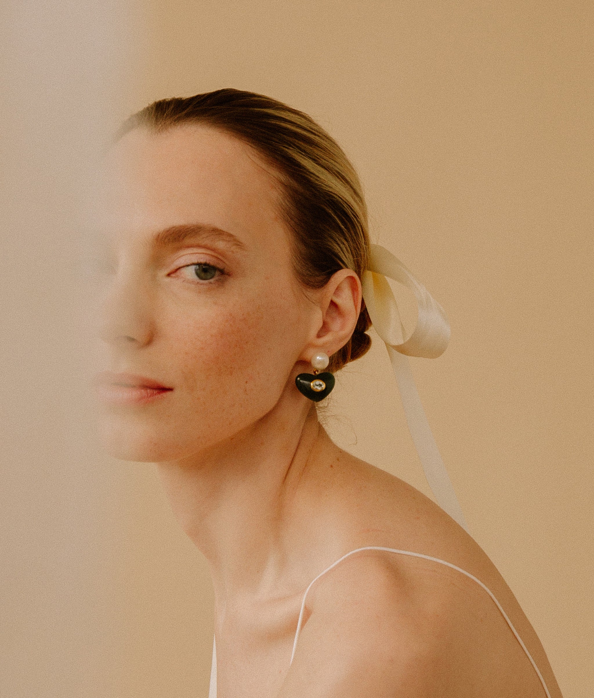 Model wearing the Enamored Earrings in Jade on a tan background.