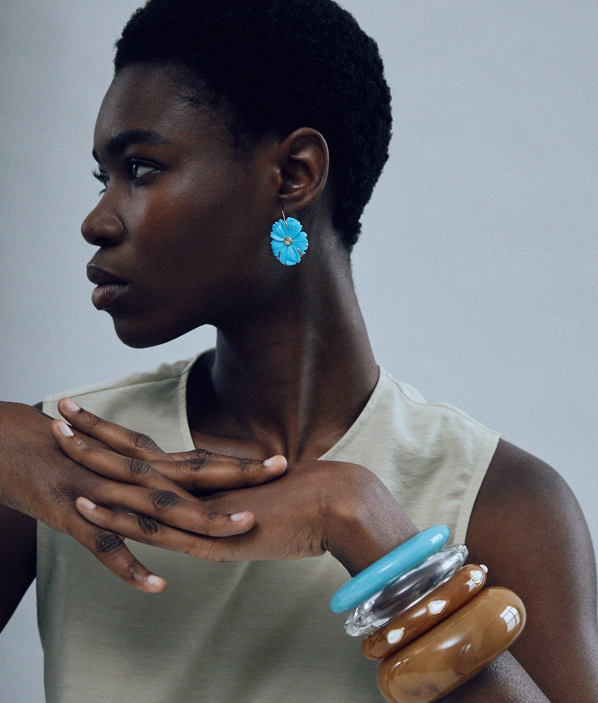 Model on grey background wearing Ridge Cuff in Marbled Aquamarine paired with ridge cuffs, arc cuff, new bloom earrings