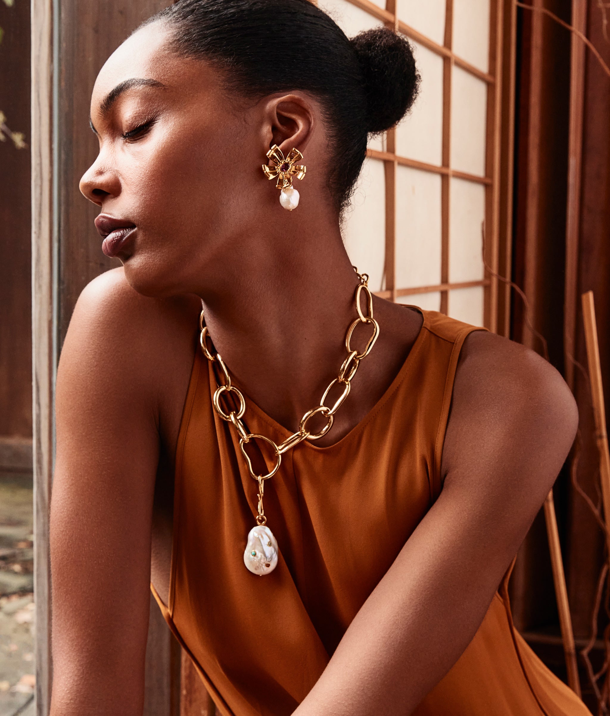 Model wears orange top with Porto Chain Necklace and Rainbow Oasis Charm.
