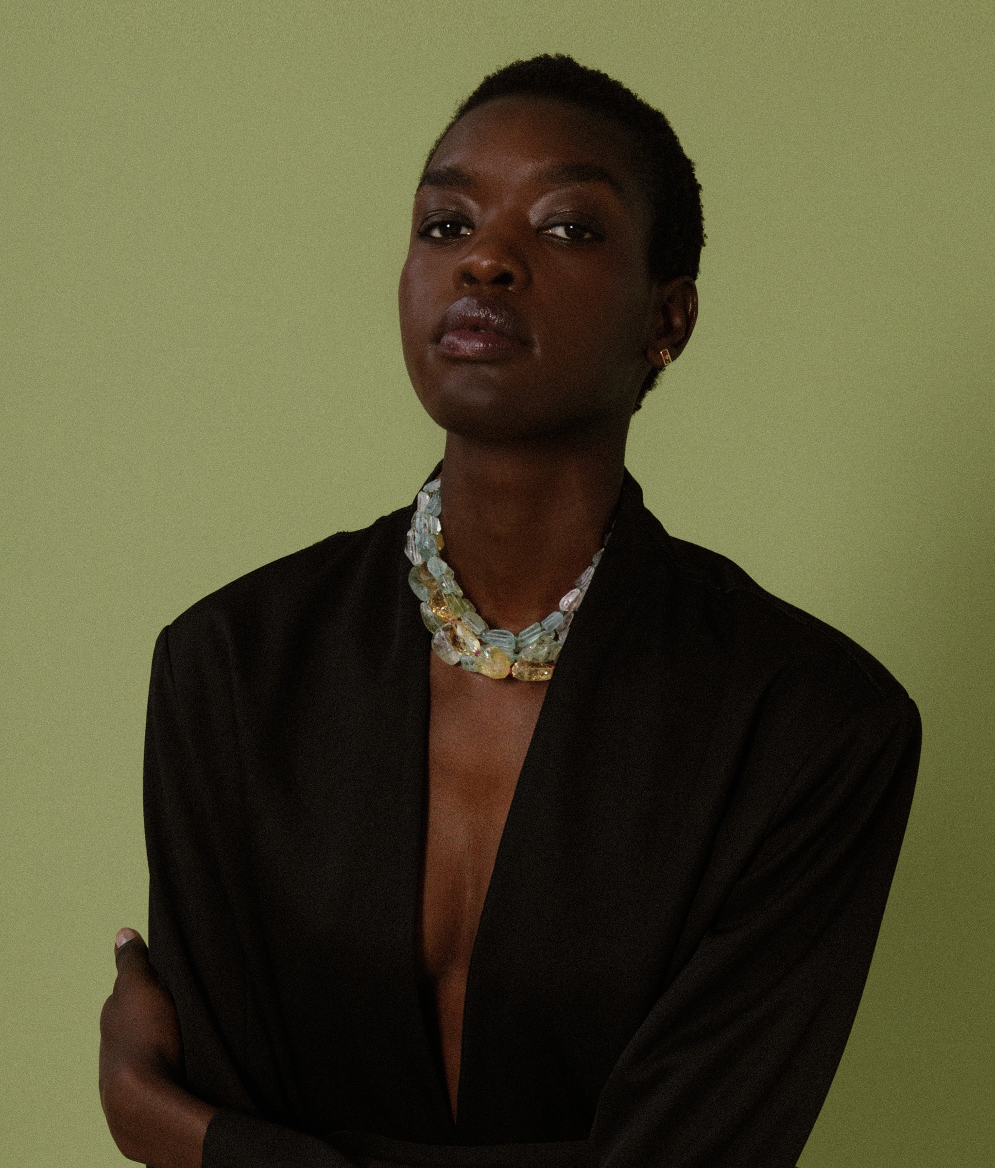 Model on green backdrop wears oversized black blazer with Small Faceted Aquamarine Nugget, Emerald & 14k Gold Necklace