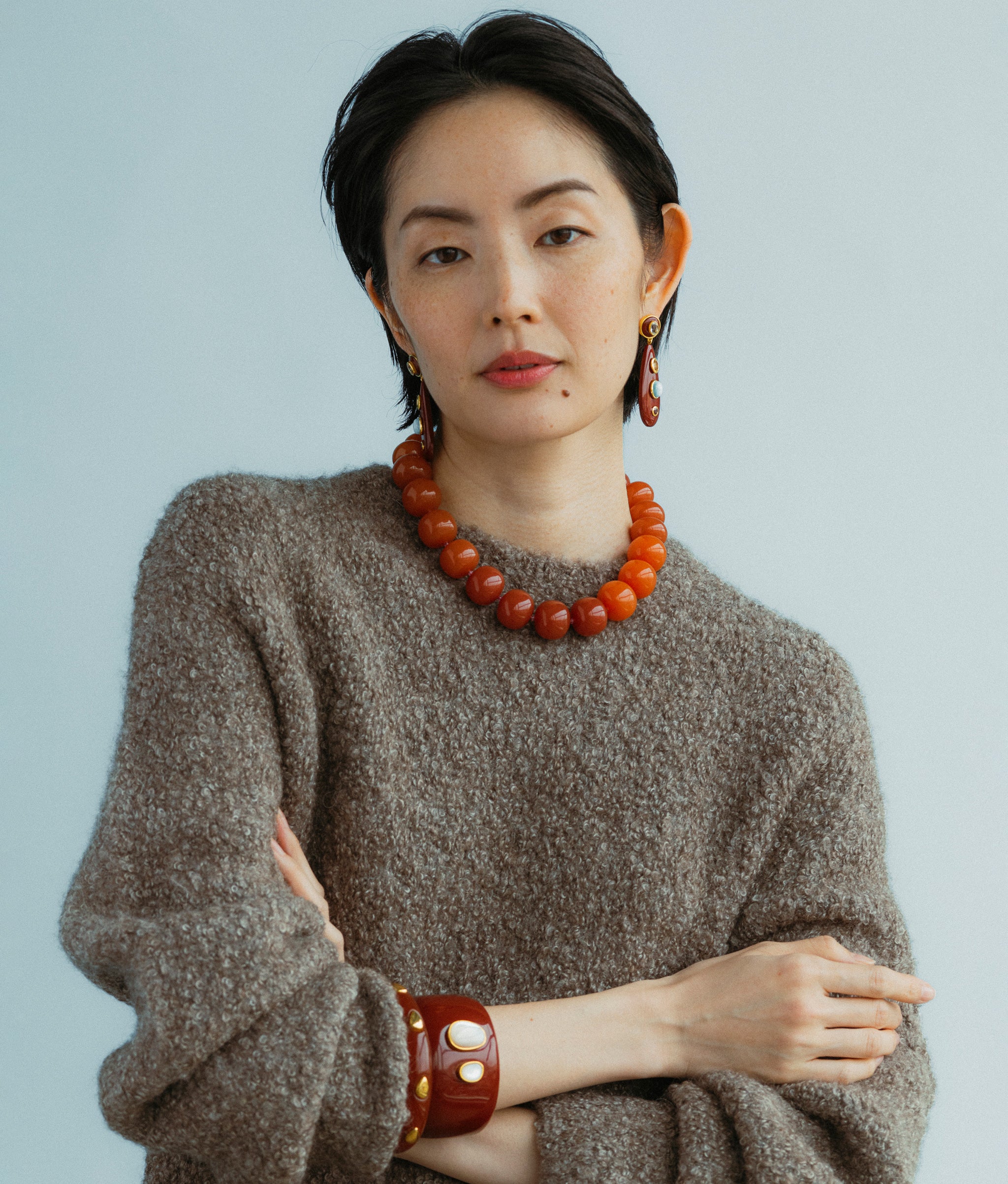 Model wears earrings paired with Olympia Collar In Spice, Ridge Cuff in Umber Gold Stud and Lanna Cuff in Pearl.