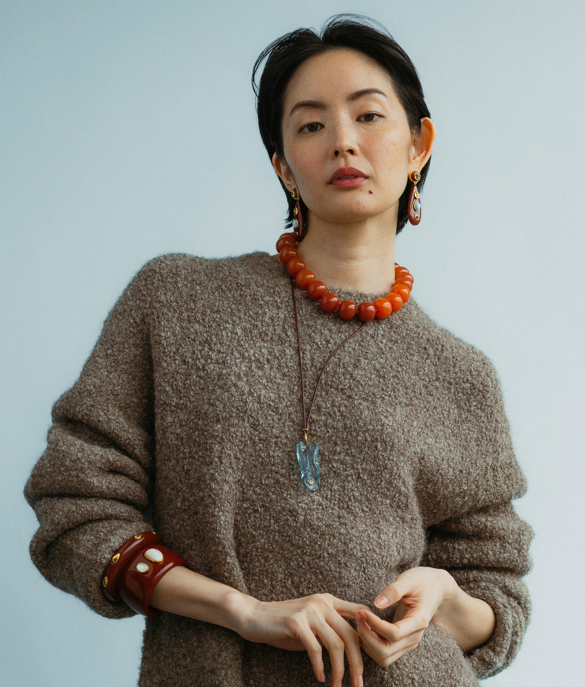 Model wears Torre Earrings in Chestnut paired with Olympia Collar In Spice, Vetri Cord Necklace and Lanna Cuff in Pearl.