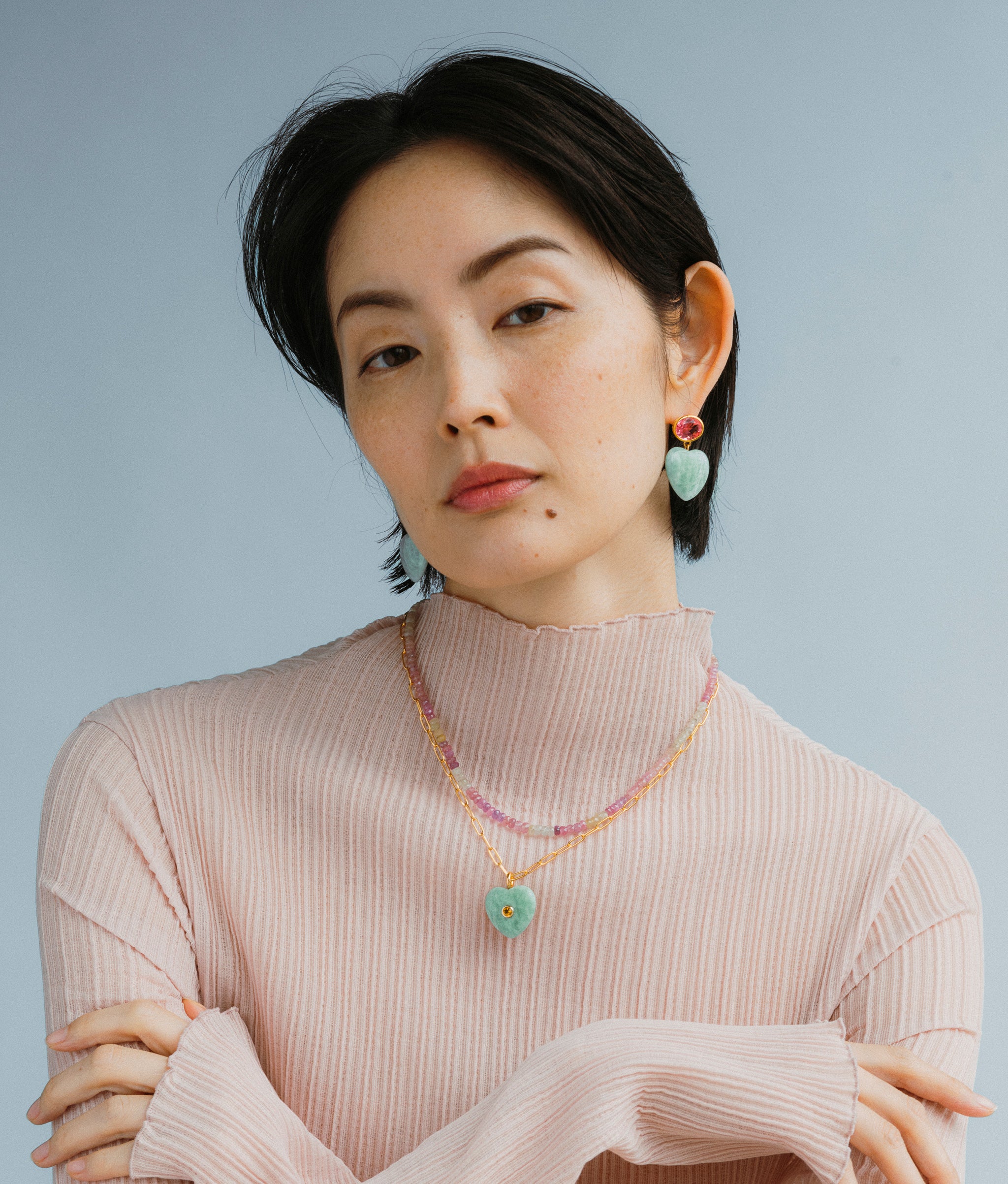 Model wears Gemma Earrings in Berry on a blue backdrop.