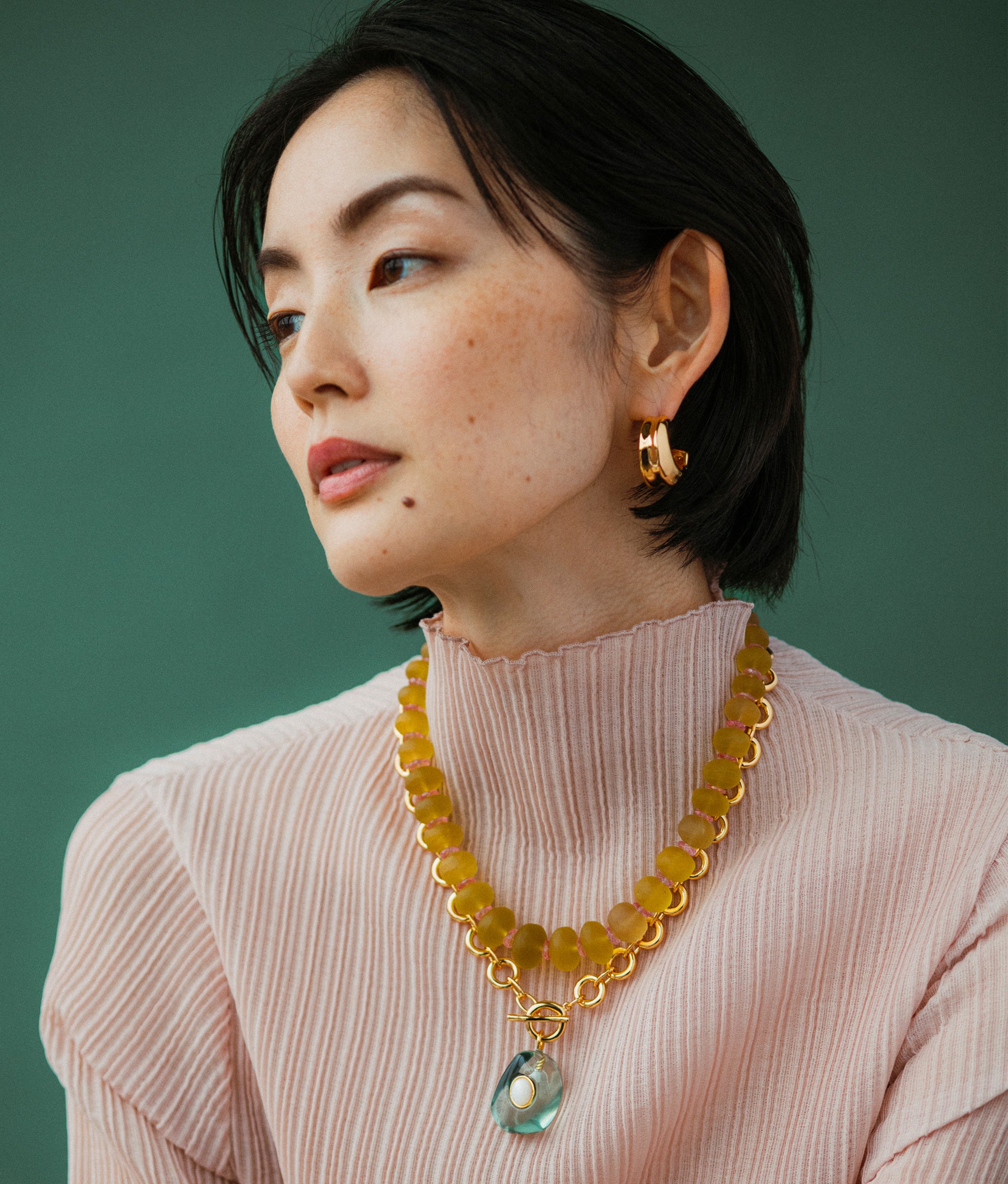 Model wears Onda Hoops In Gold styled with Meteor Necklace in Sea and Canary Cliffs Necklace.