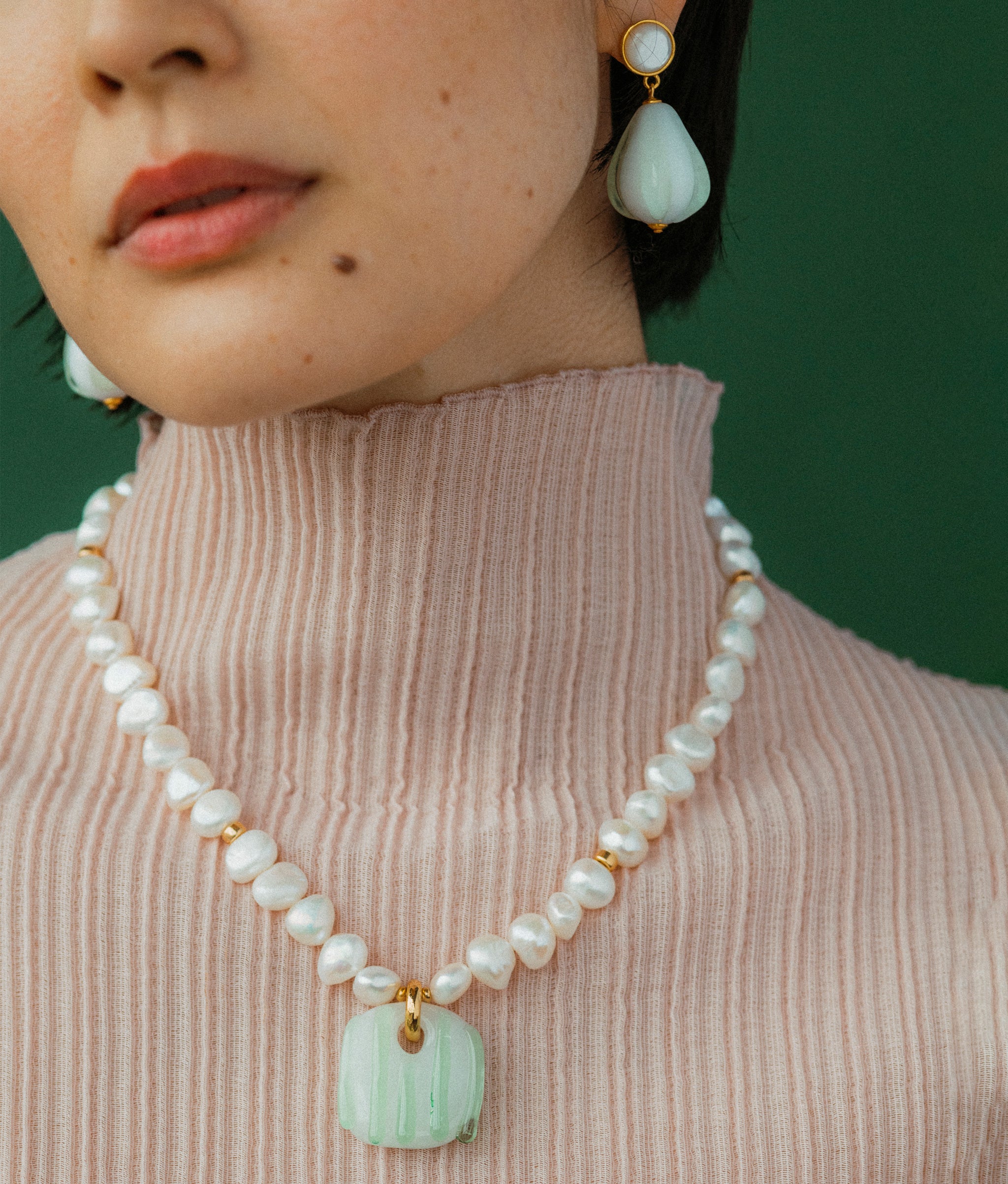 Close-up of Sean Bean Earrings and Marine Glass Necklace on model.