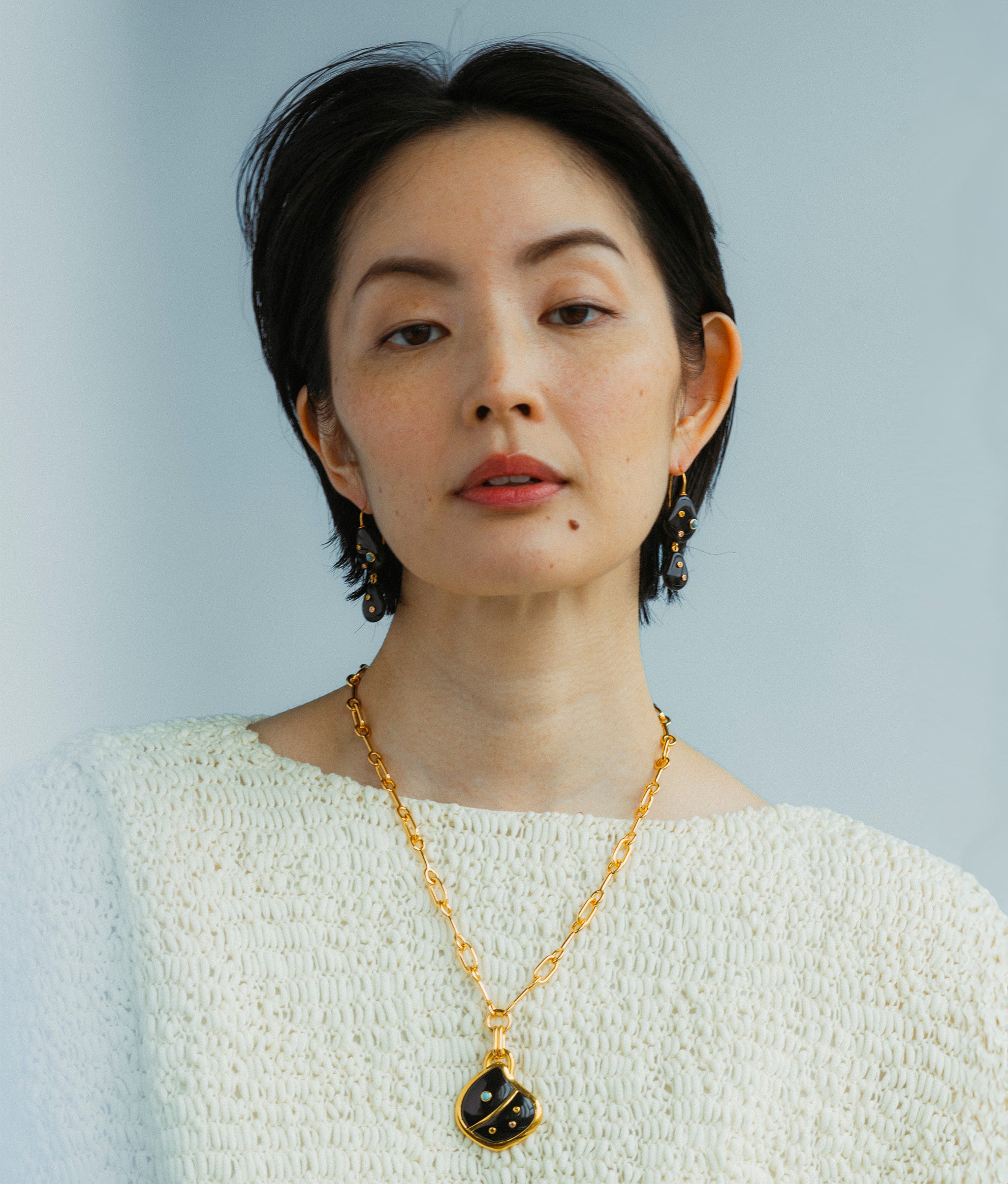 Model wears Stacked Stone Earrings in Black Agate paired with Agate Shell Pendant Necklace