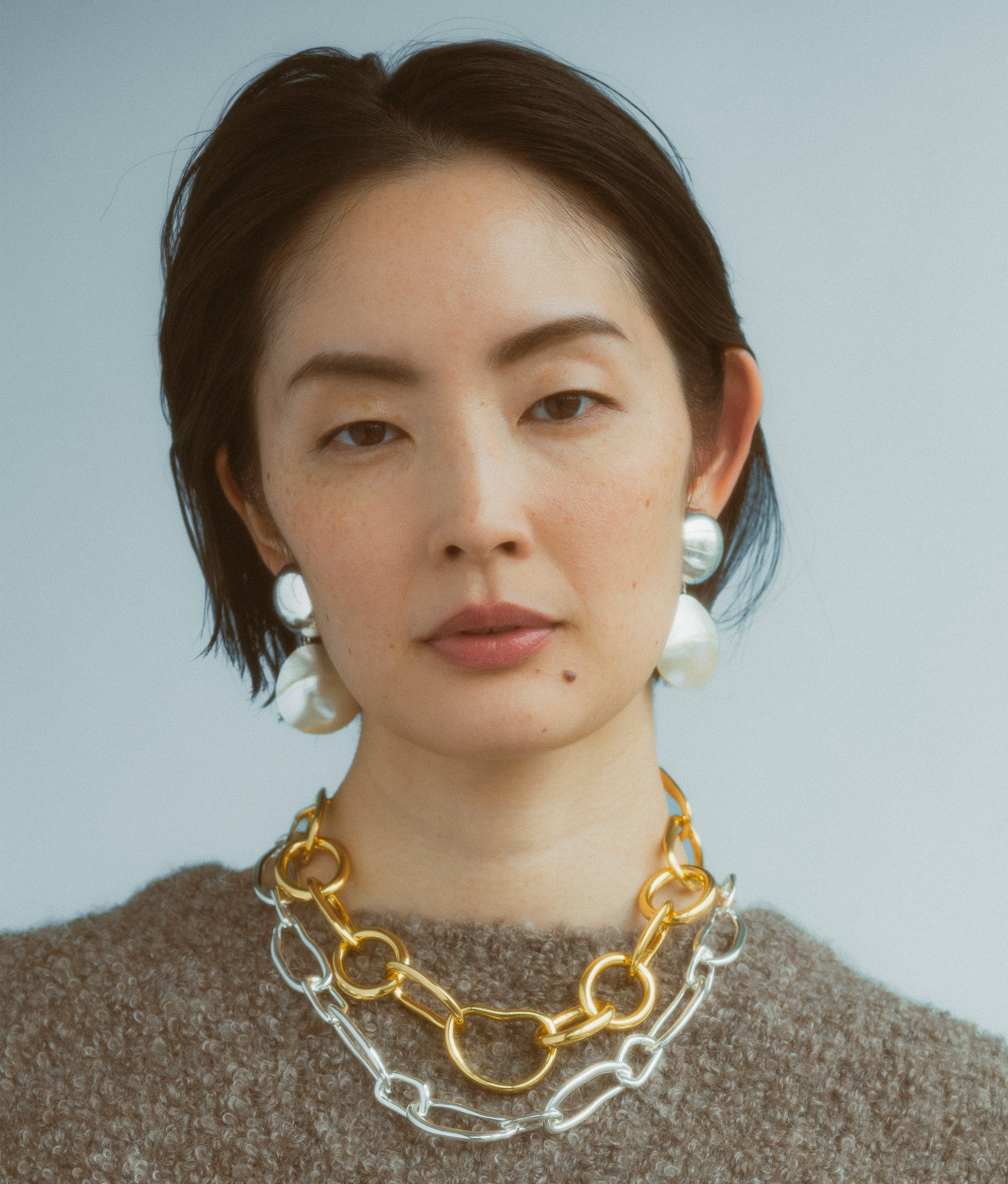 Model wears Rodan Pearl Earrings In Silver along with Collage Chain Necklace In Silver and Porto Chain.