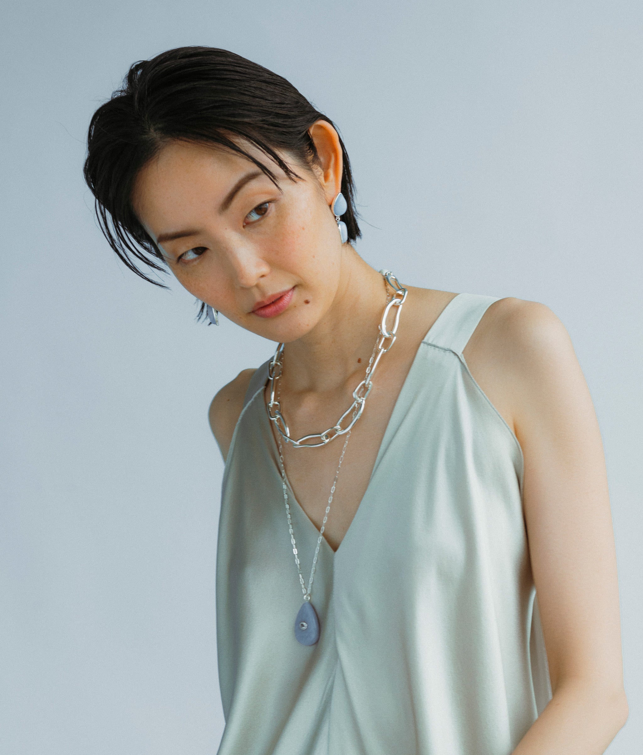 Model wears Electra Earring in Angelite along with Collage Chain Necklace In Silver and Avalon Necklace