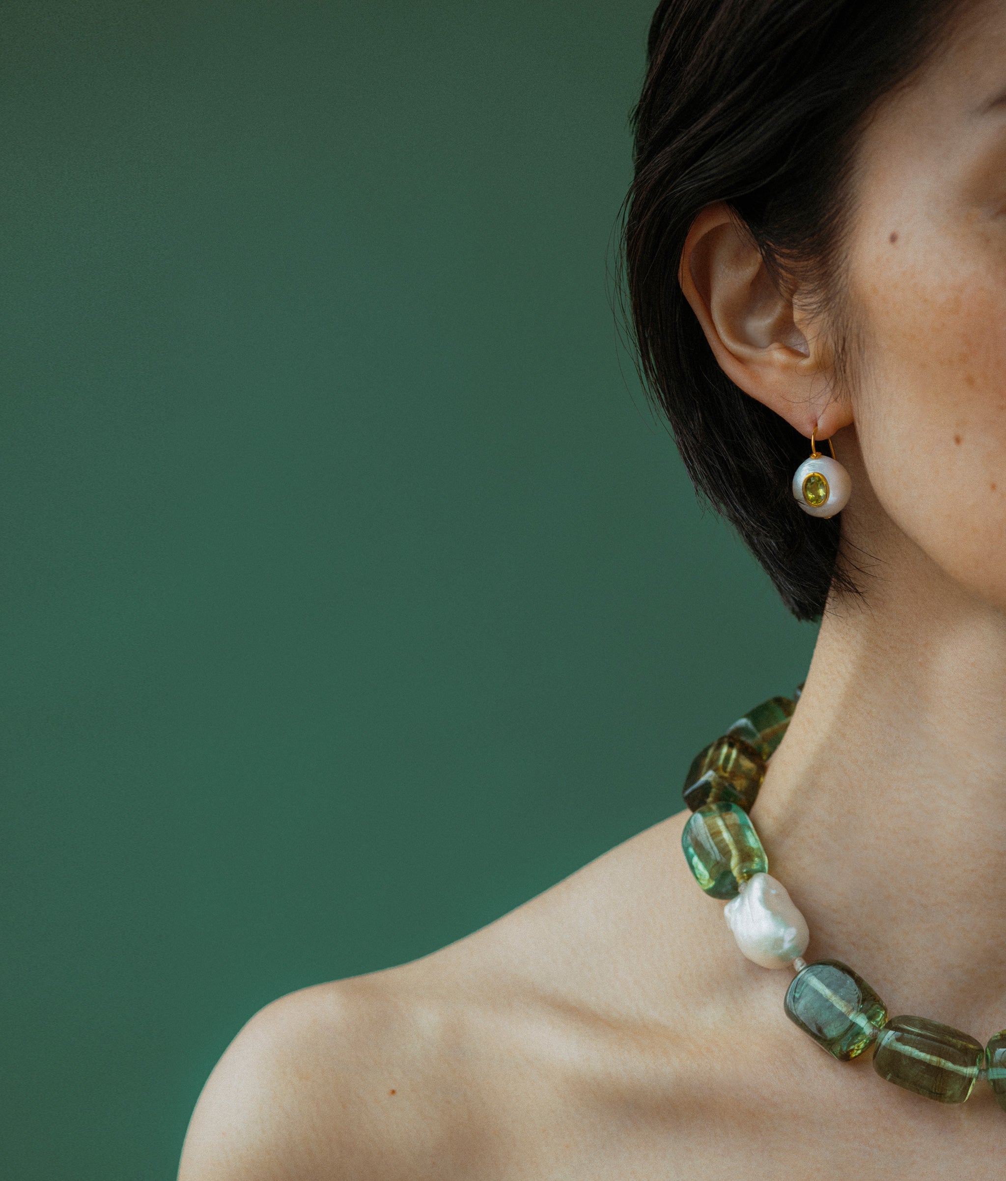 Close-up of model wearing Delphine Collar with Pear Pablo Earrings In Peridot