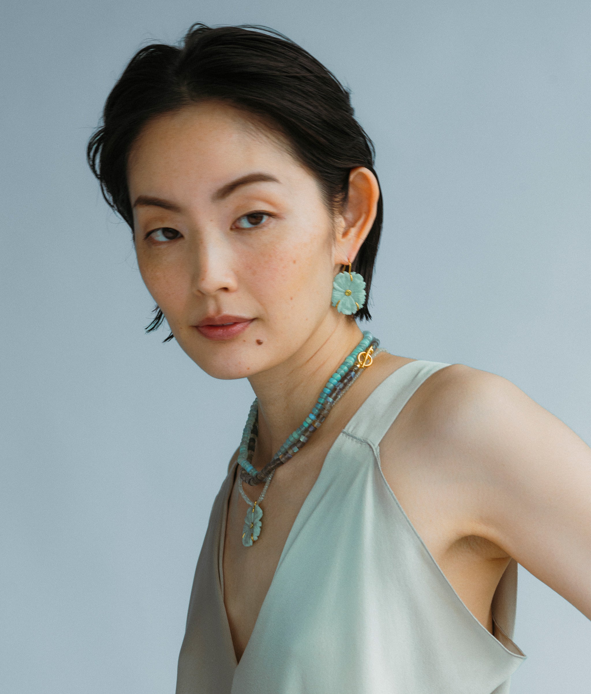 Model wears Sea Grass Necklace styled New Bloom Earrings in Sea Foam and an overlayed necklace.