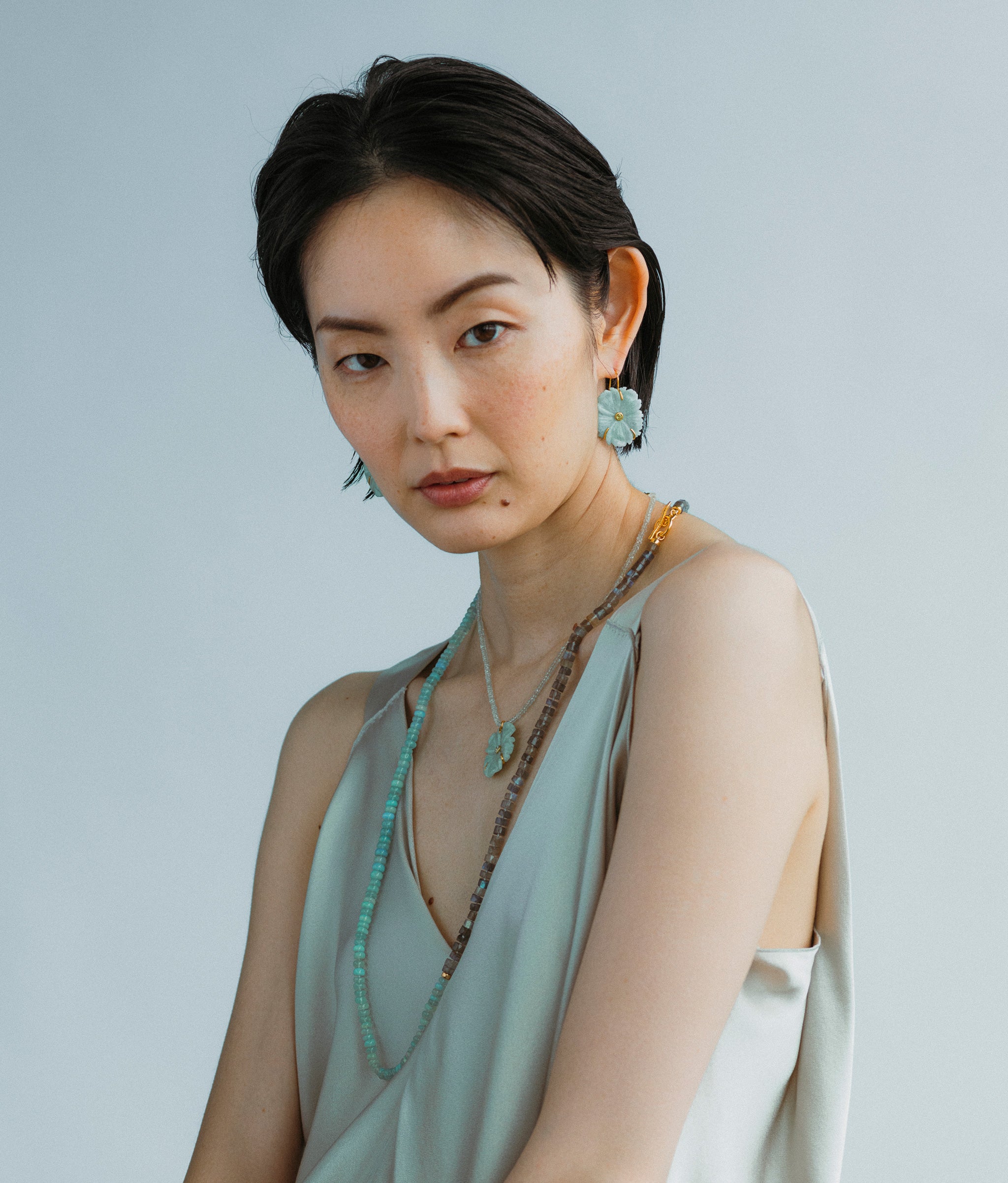 Model wears Sea Grass Necklace styled New Bloom Earrings in Sea Foam and an overlayed necklace.