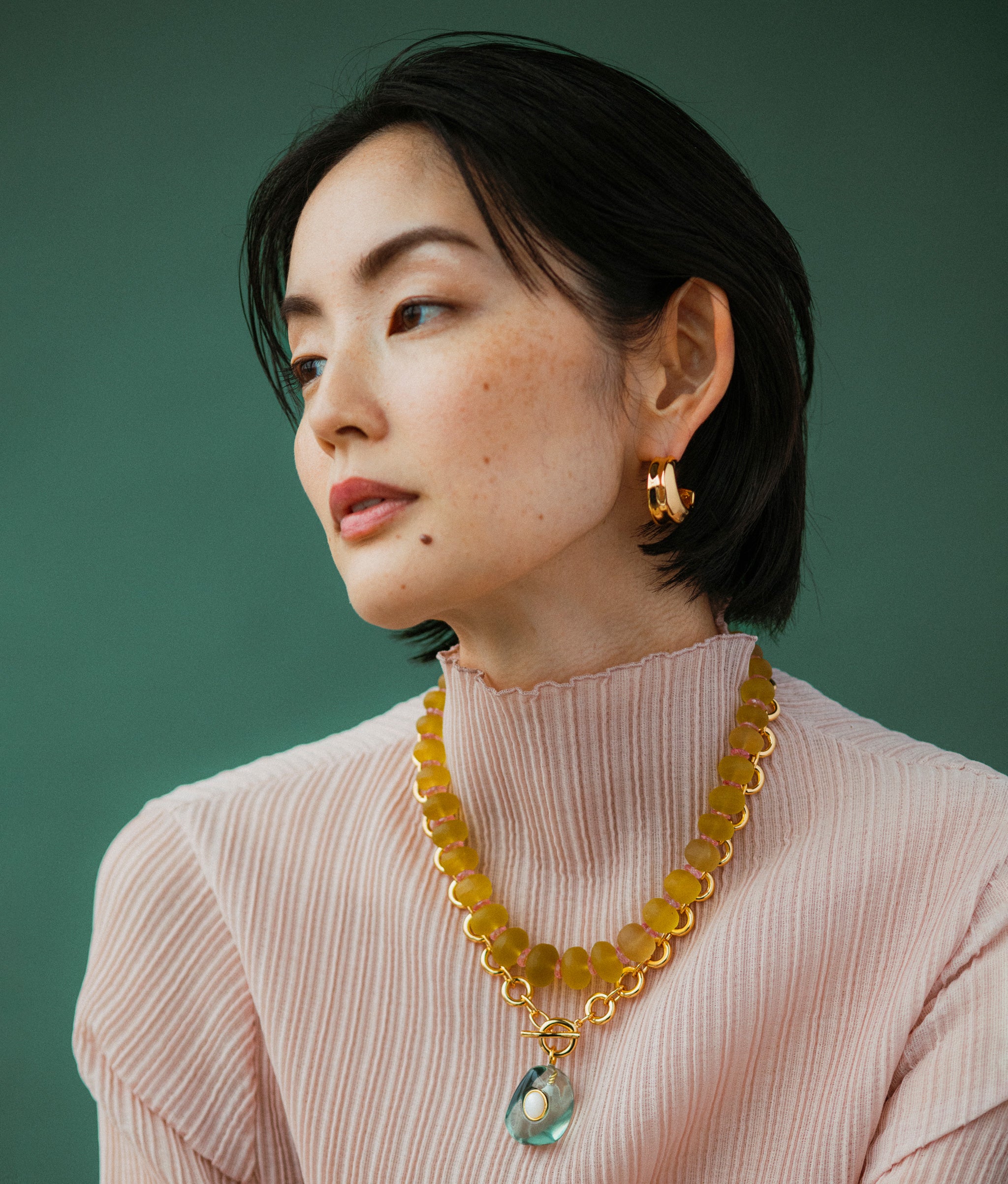 Model wears Canary Cliffs Necklace with Meteor Necklace in Sea on a green backdrop
