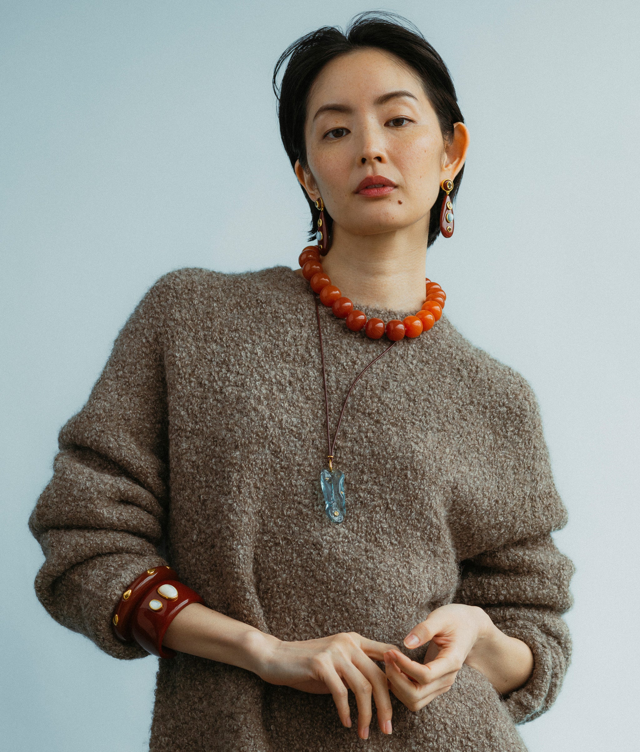 Model wears Torre Earrings in Chestnut paired with Olympia Collar In Spice, Vetri Cord Necklace and Lanna Cuff in Pearl.