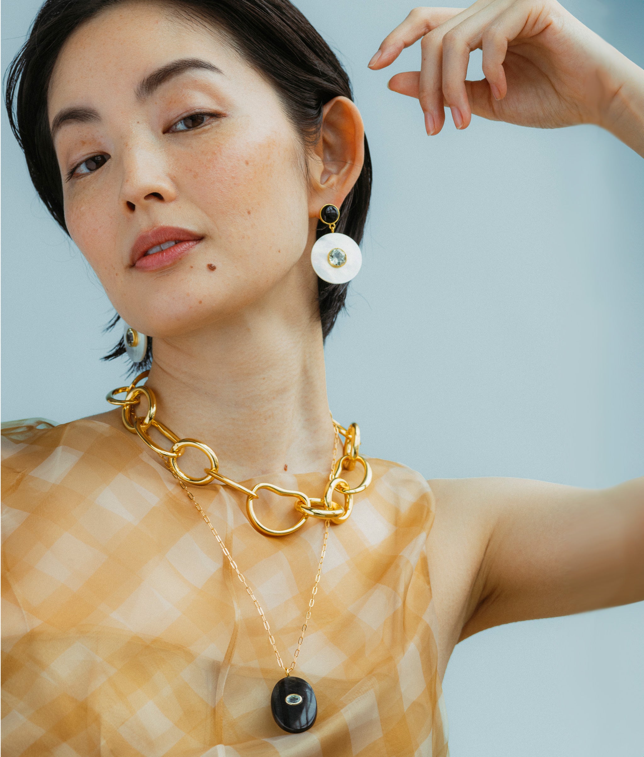 Model wears Tigre Pendant Necklace overlayed with Porto Chain and Taj Disc Earrings In Mother-Of-Pearl