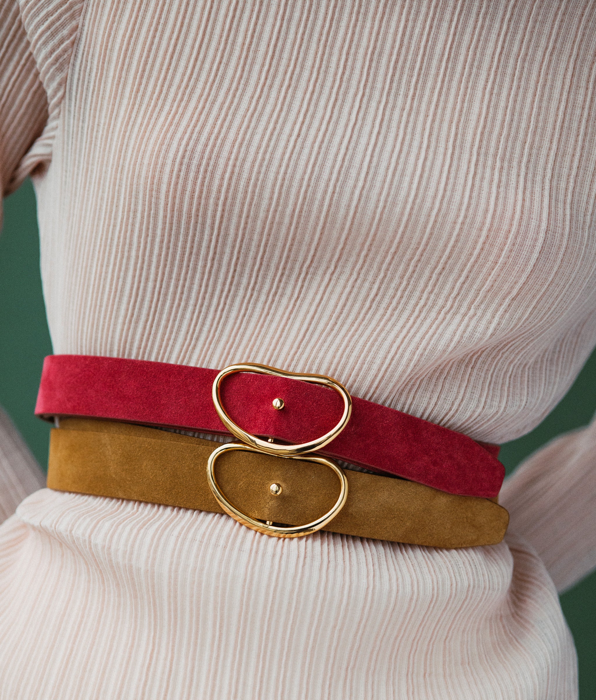 Close-up of model wearing two Wide Georgia Belts in a green backdrop.