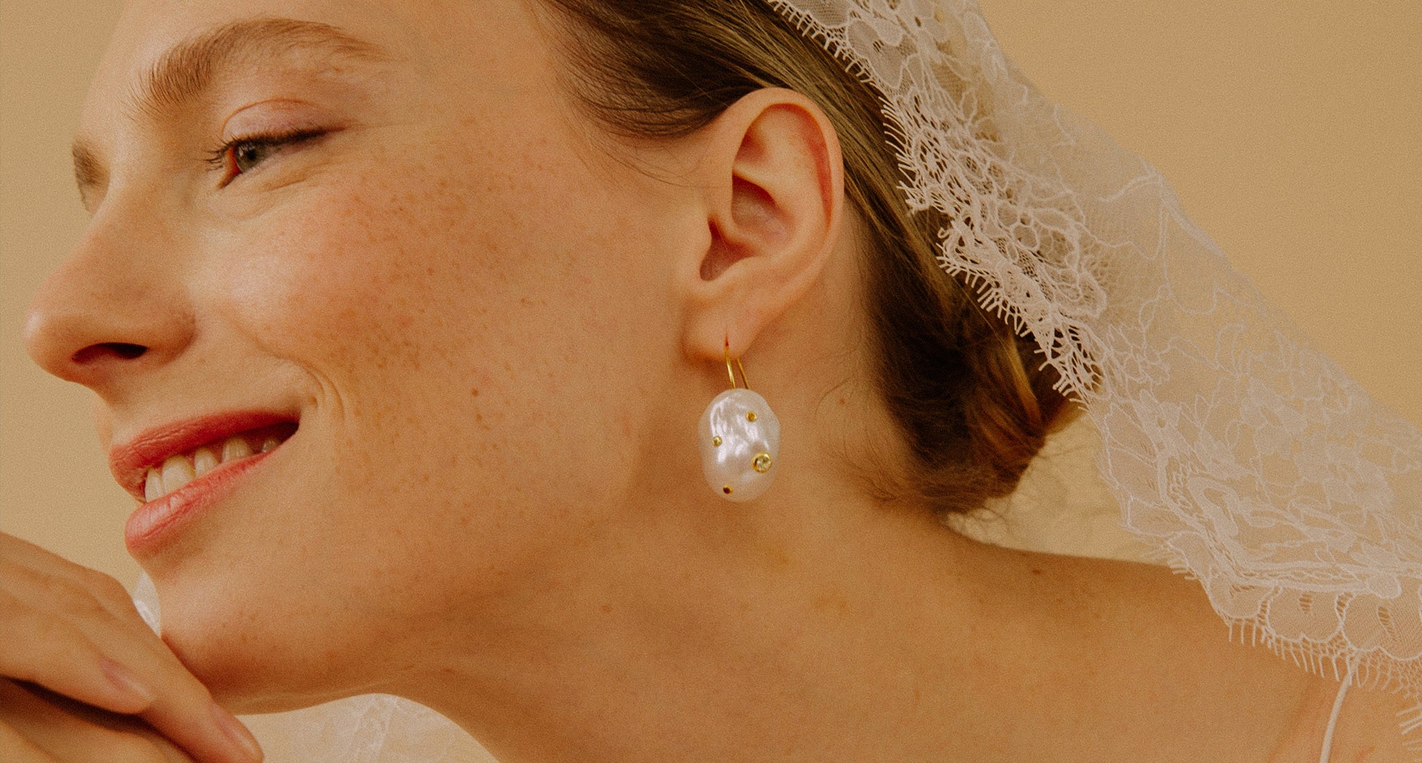 Model in profile wears Eros Earrings with white lace veil