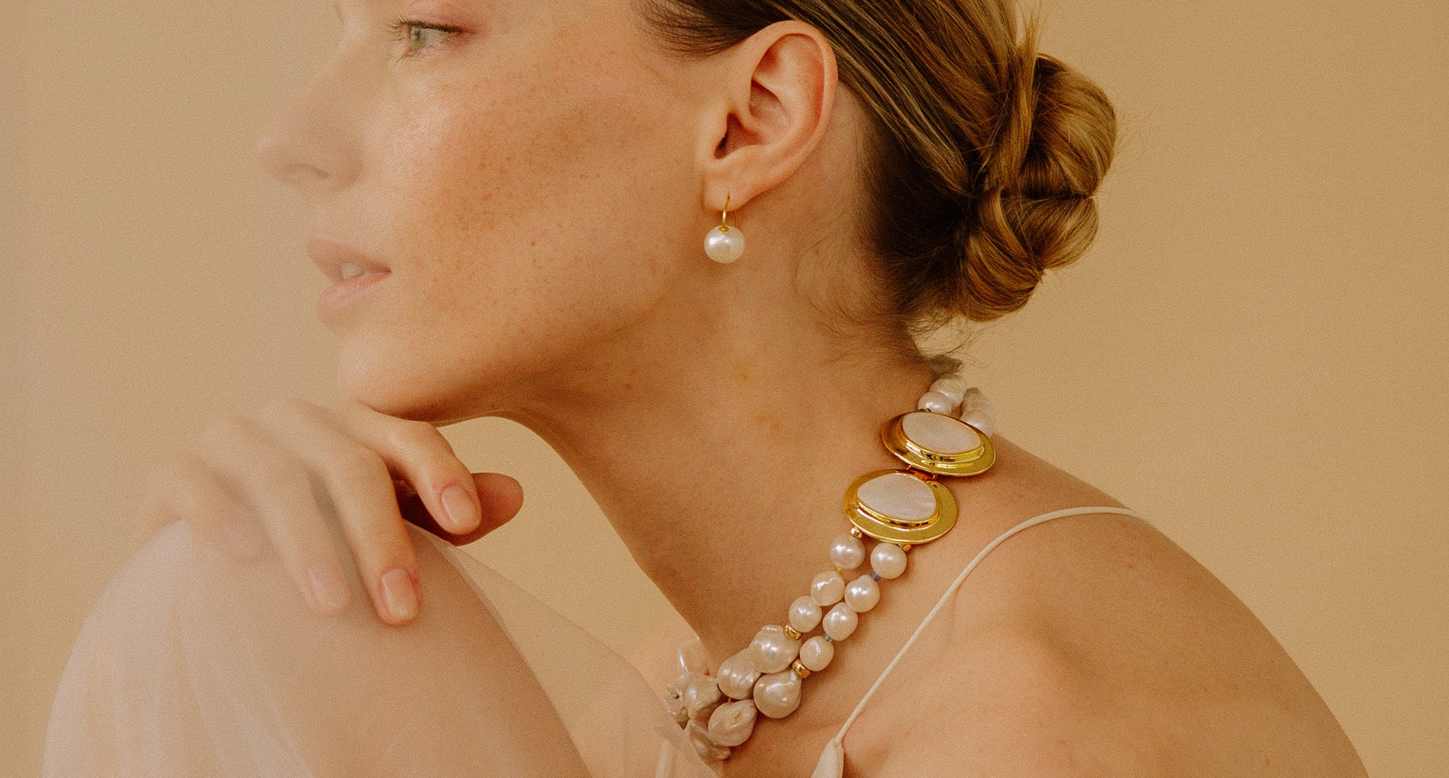 Model in profile rests chin on hand, wears Monte Palace Necklace and Pearl Earrings