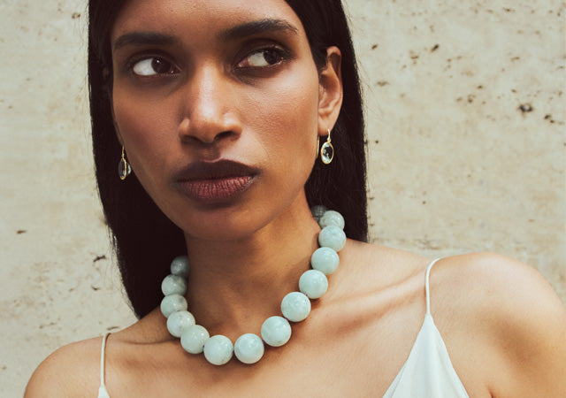Model on stone backdrop wears Green Angelite bead Necklace and Pool Earrings