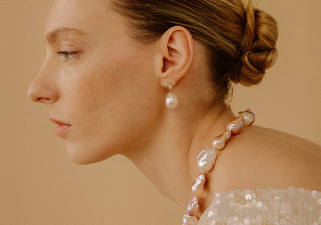 Model in profile on tan backdrop wears Estate Pearl Necklace and Palazzo Earrings