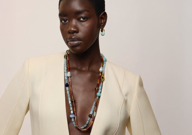 Model on grey backdrop wears cream jacket with beaded Circo Necklaces