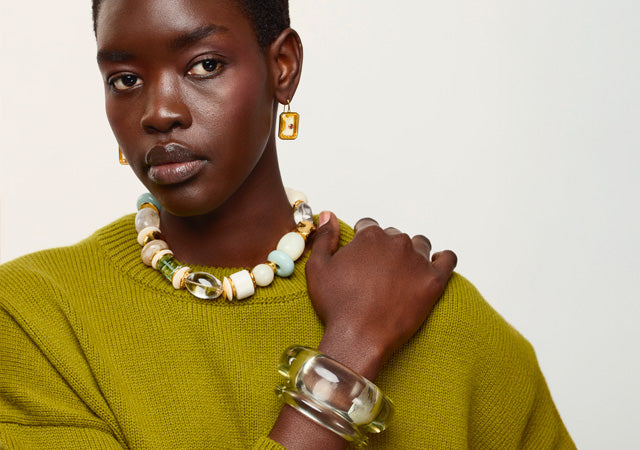 Model in chartreuse sweater wears Monument Collar, cuffs in lime, and Tile Earrings