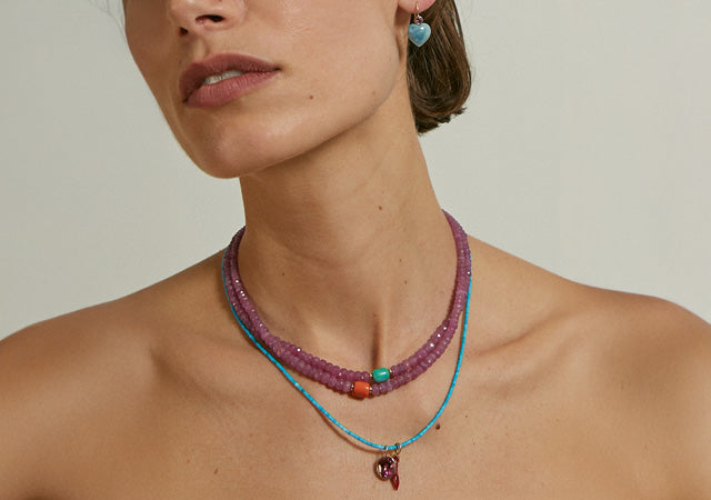 Close-up of model's chest wearing two pink sapphire bead necklaces and tiny turquoise necklace