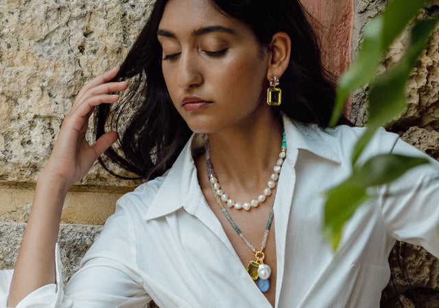Model in white shirt wears pearl and bead necklaces and Lush Earrings