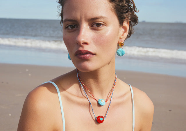 Model on beach wears Kai Necklaces and Kai Earrings