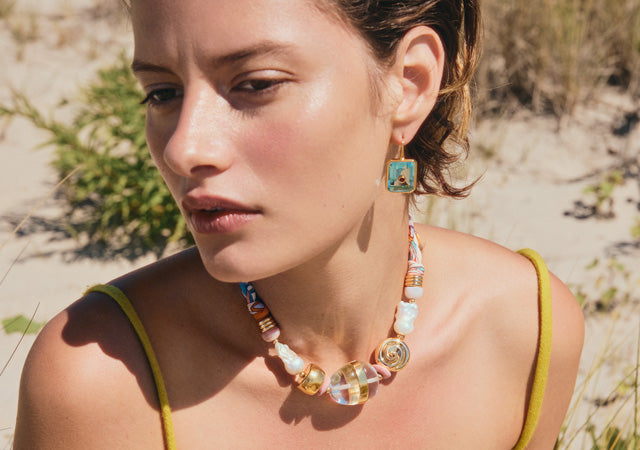 Model on beach wears Tile Earrings and Glass Beach Necklace