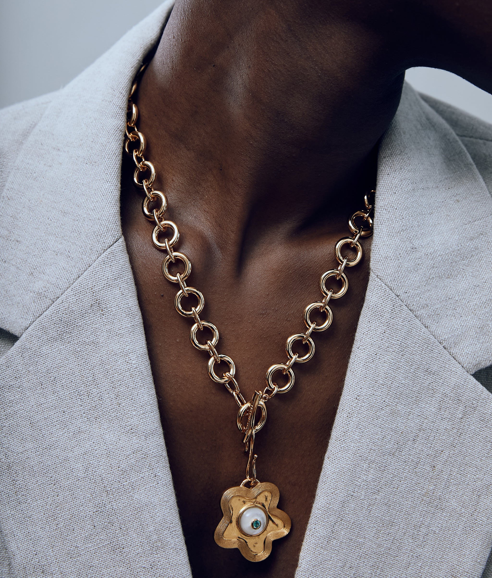 Close-up of model wearing the Mood Necklace in Gold with gold star-shaped charm attached on grey background.