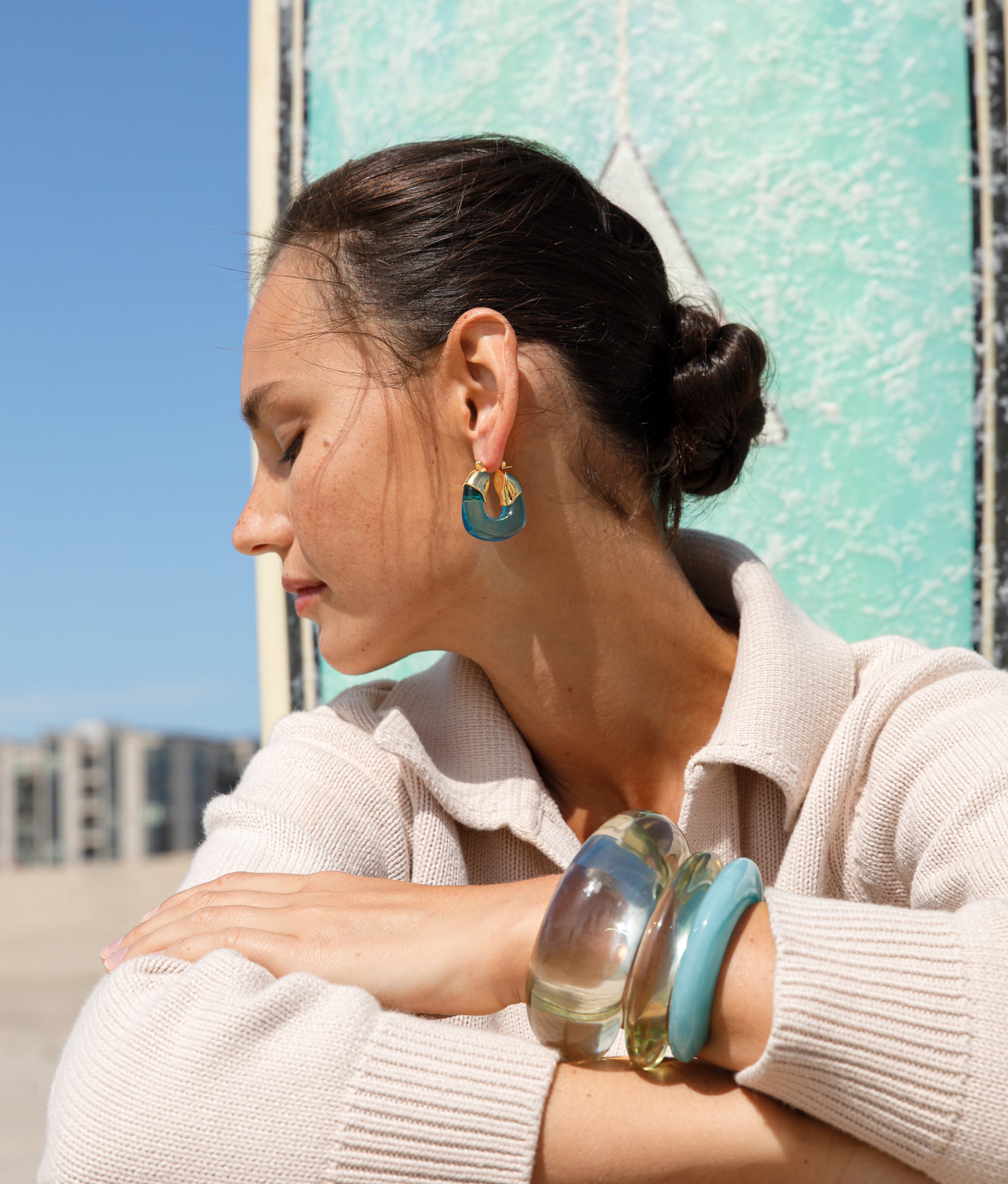 Side angle of model wearing Organic Hoops in Turquoise paired with Arc and Ridge Cuffs in Lime and Marbled Aquamarine.