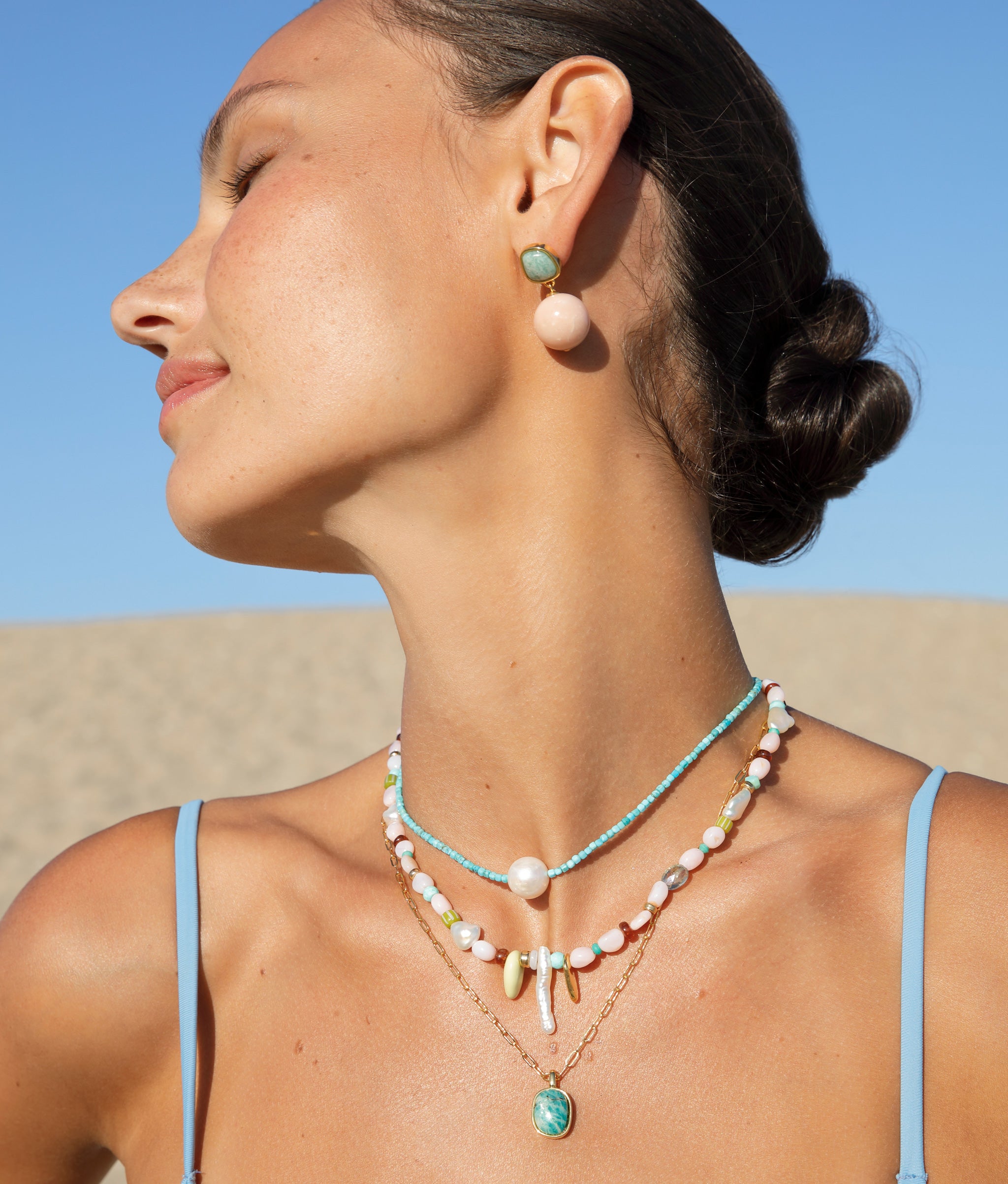 Close-up of model wearing the Off Shore Necklace in Pink Sands with the Rio Earrings in Blush.
