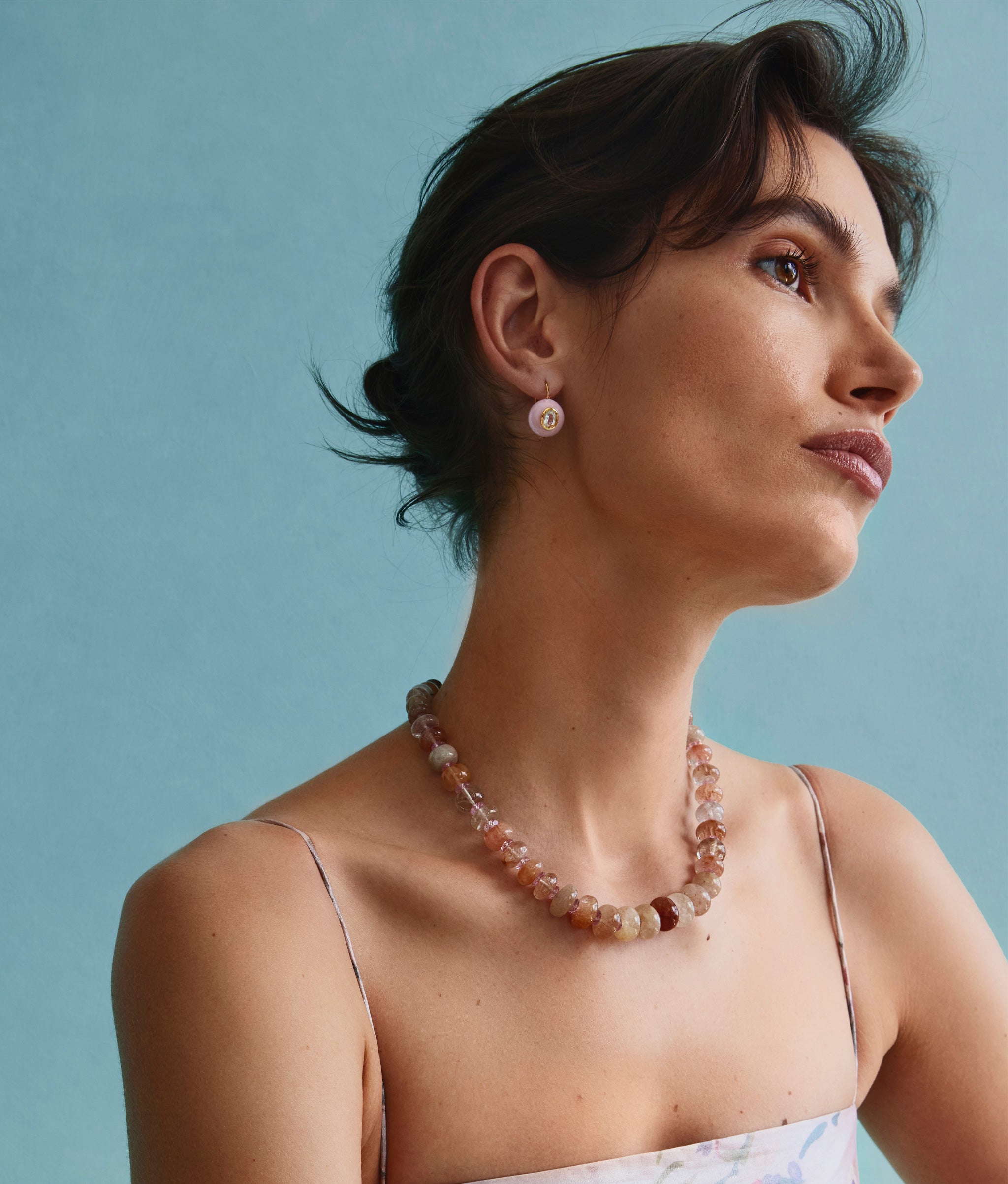 Model on blue backdrop wearing strappy dress with Pablo Earrings in Rose and Pink Cliffs Necklace.