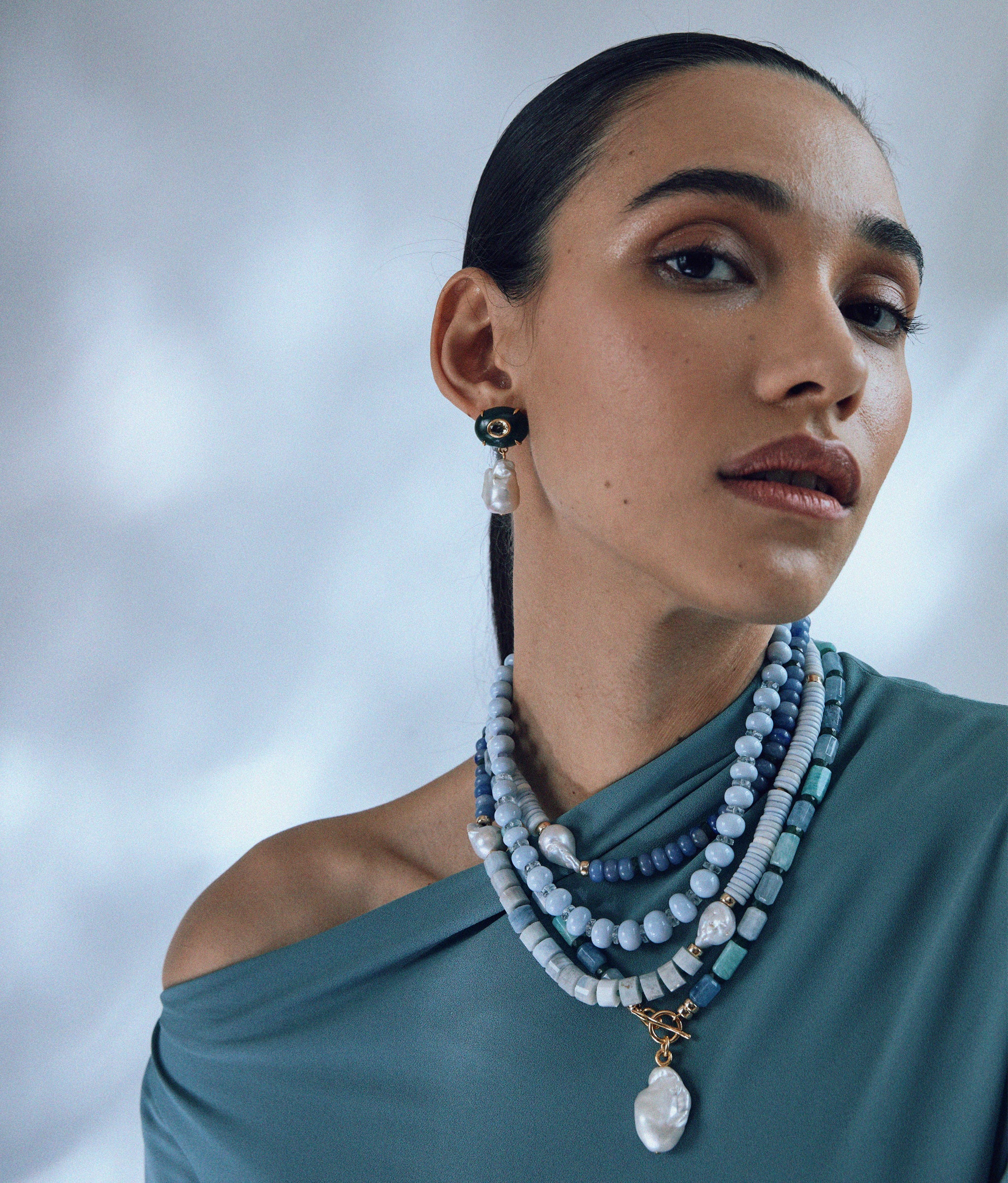 Model wears Pearl Isle Necklace in Sea layered with Cabana necklace in Azure Sky and Plaza Pearl Earrings in Jade.