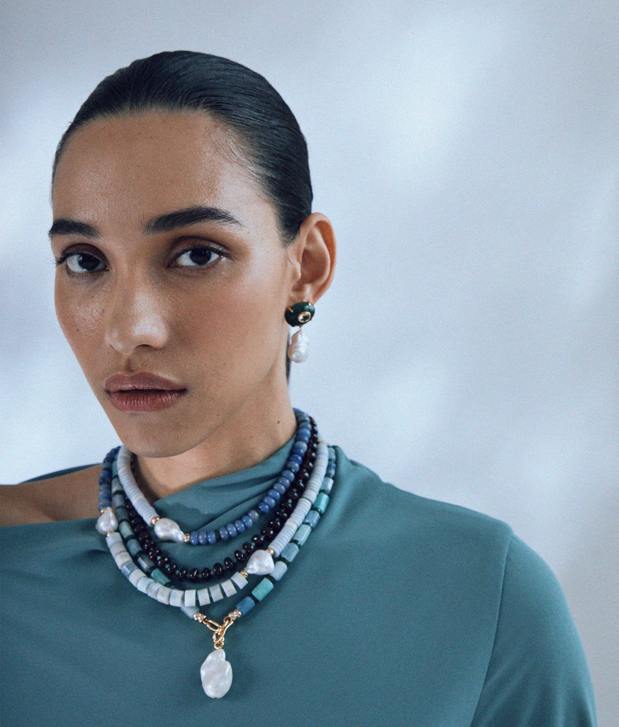 Model wears Pearl Isle Necklace in Sea layered with Cabana necklace in Azure Sky and Plaza Pearl Earrings in Jade.