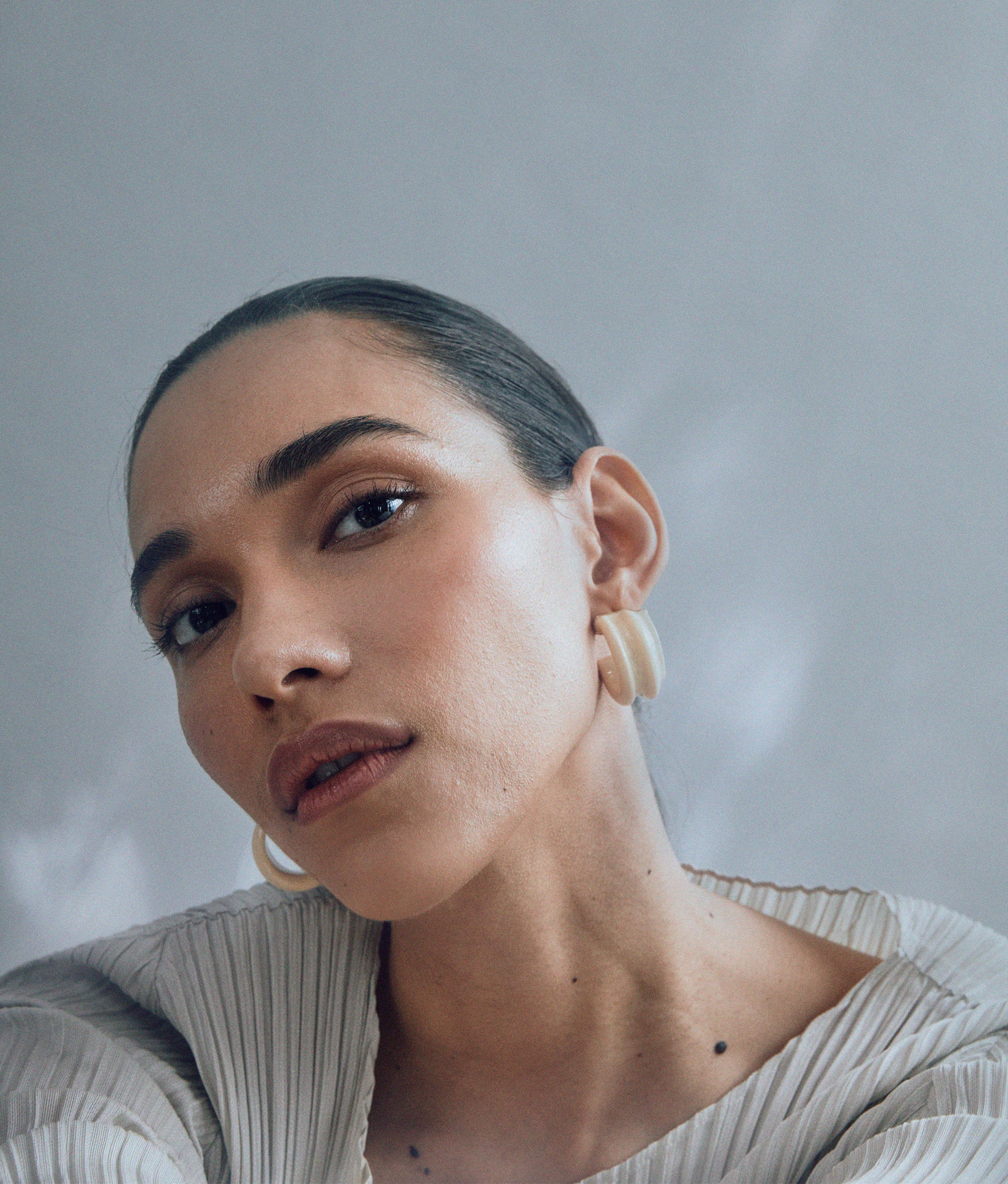 Model wears Sculpted Hoops In Cloud tipped with gold.