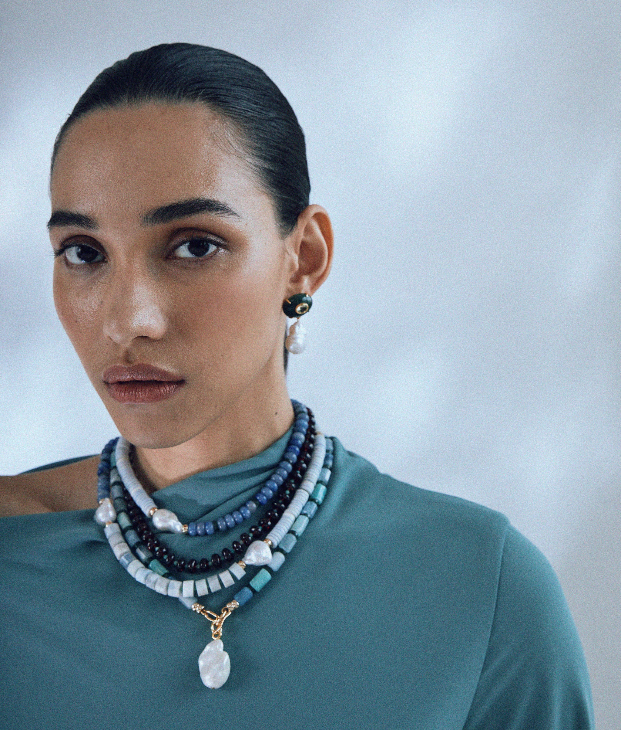 Model wears Tola Necklace in Eclipse layered with Pearl Isle Necklace in Sea and Plaza Pearl Earrings in Jade.