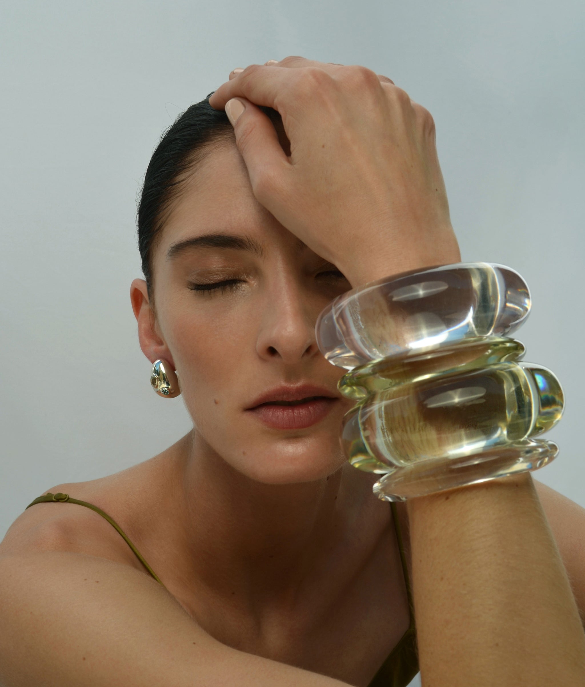 Model wearing Arc Cuff in Lime paired with Arc Cuff in Lilac, Ridge Cuffs in Lime and Lilac, and chunky gold studs.