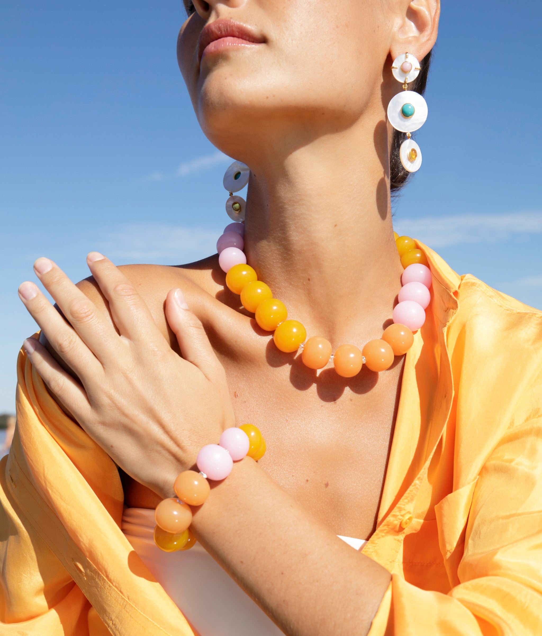 Close-up of model wearing Olympia Bracelet and Collar paired with Tropic Pearl Earrings.