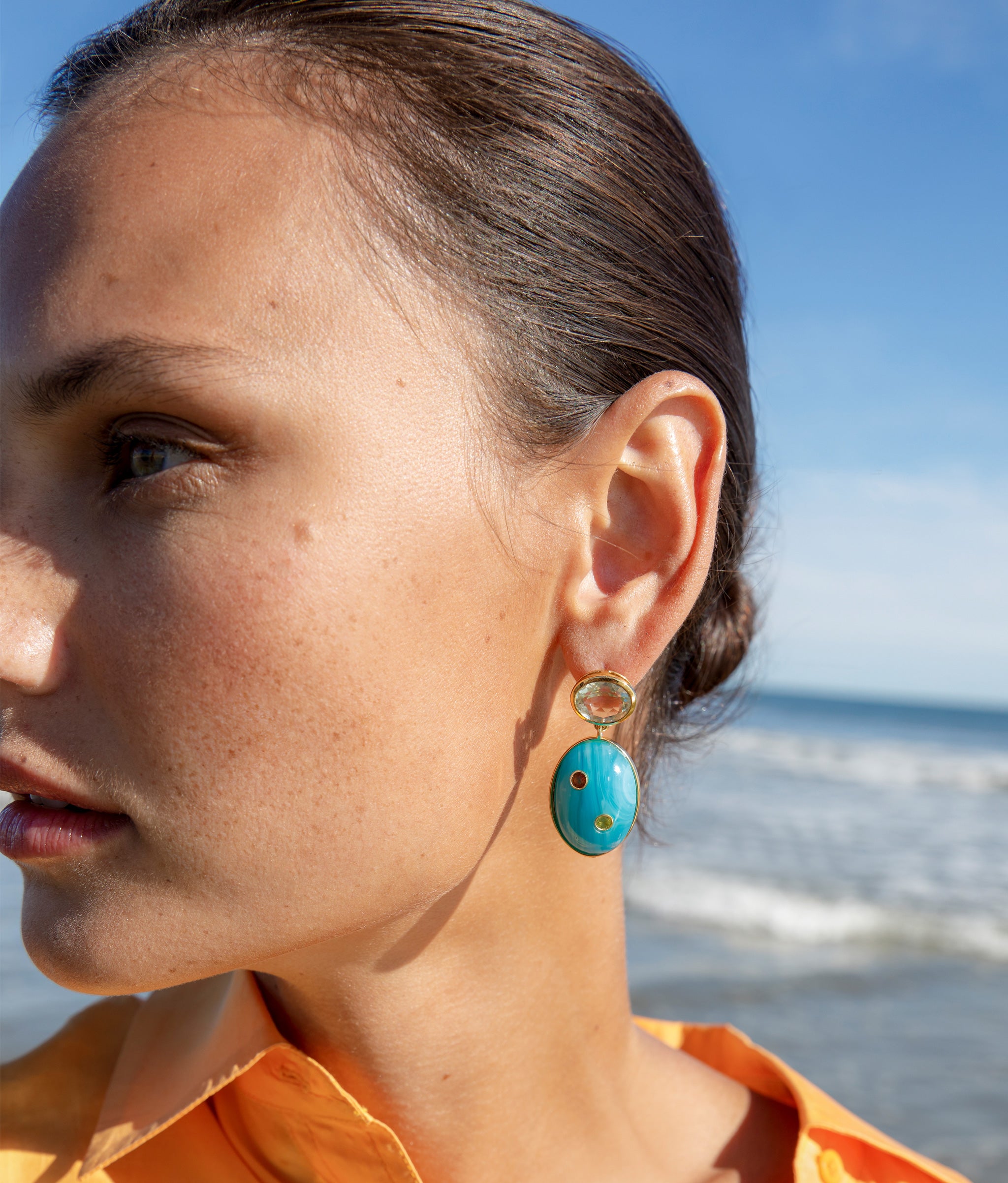 Close-up of model at the beach wearing the Blue Mountain Earrings.